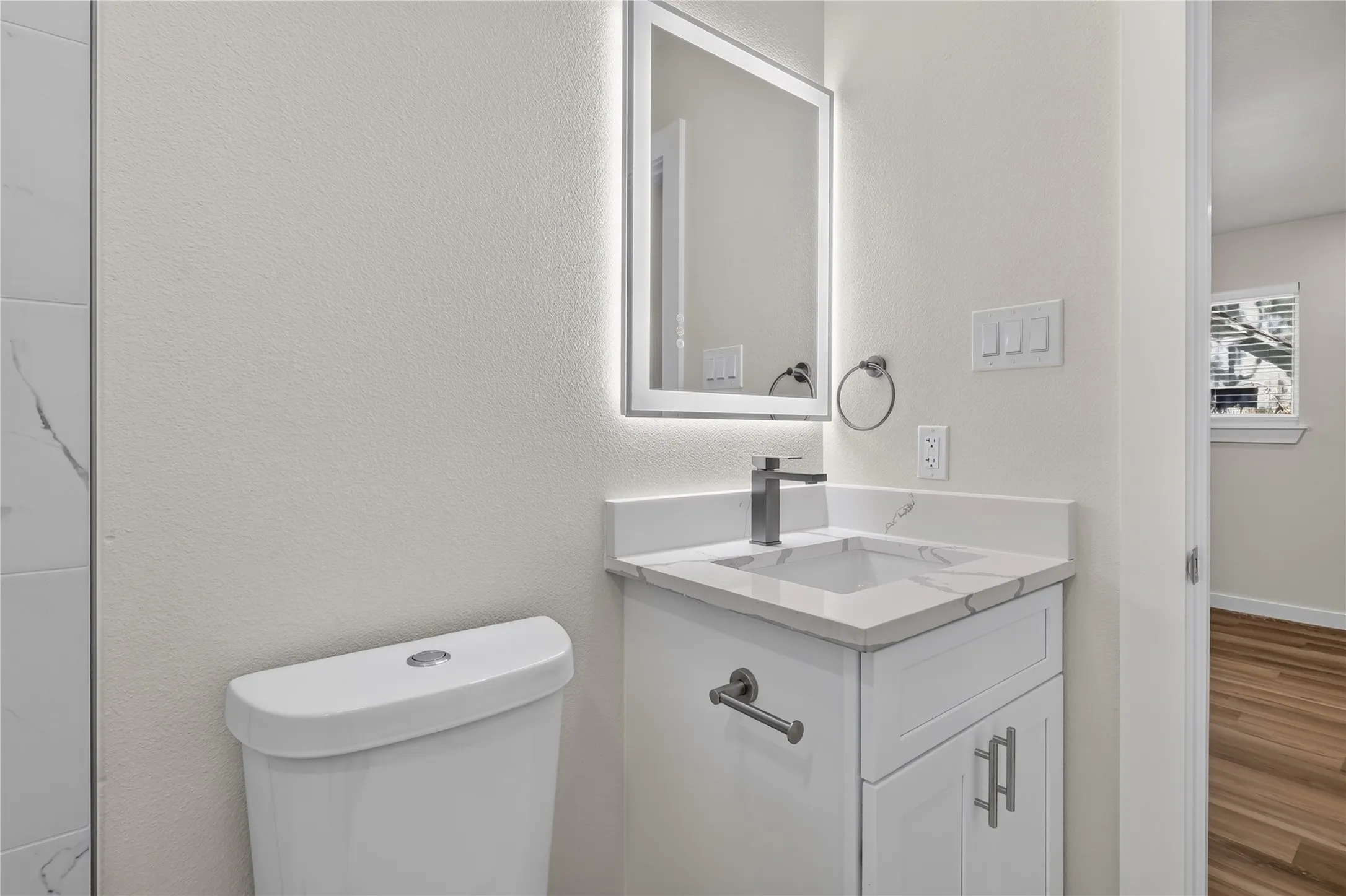 White vanity with a rectangular undermount sink, quartz-finish countertop, and brushed nickel faucet