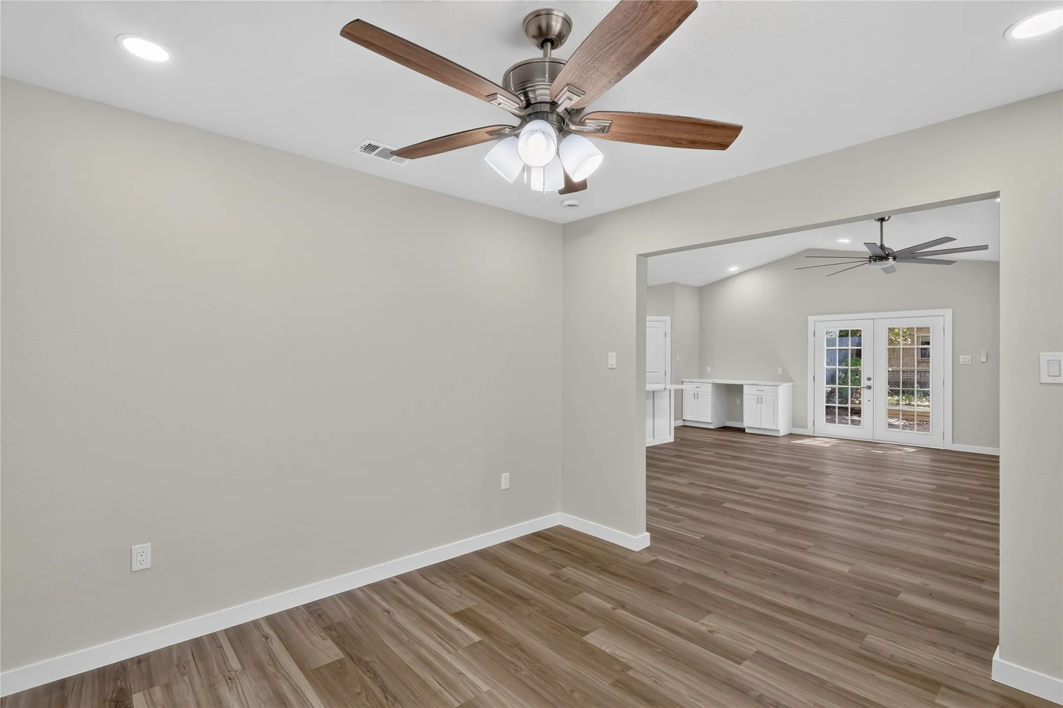 Wood-finish flooring, recessed lighting, ceiling fan with light kit, and a wide cased opening to an additional room