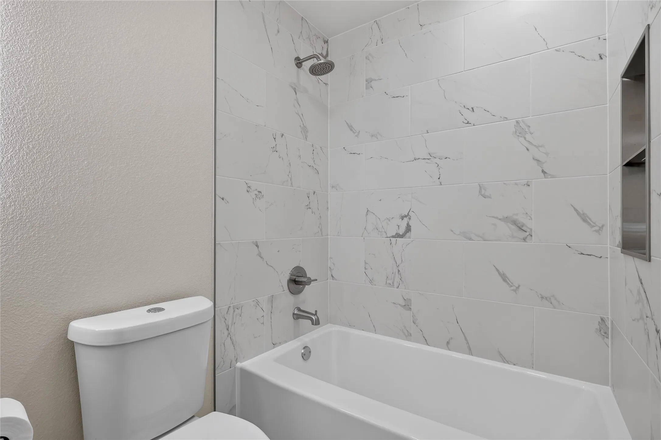 Subway tile shower surround with integrated niche, chrome fixtures, and a white soaking tub