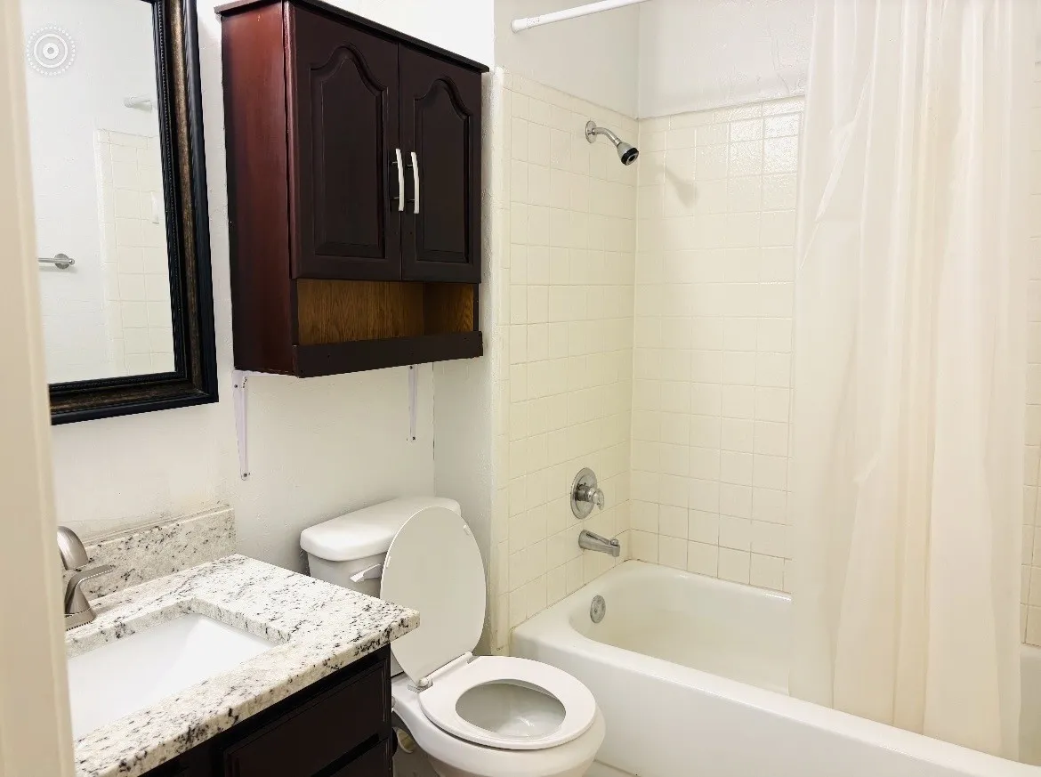 Granite-finish countertop with an undermount sink, built-in medicine cabinet, and a tiled shower/tub combination