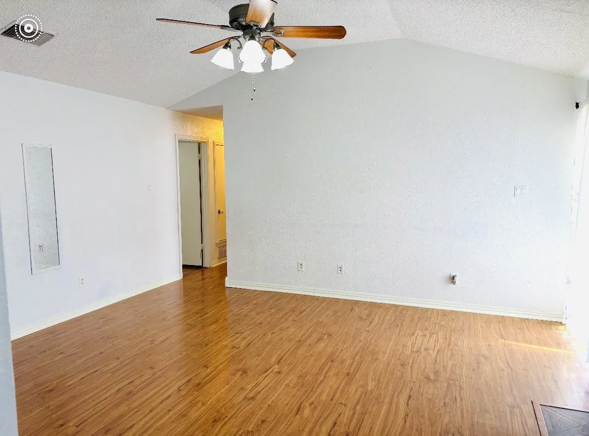 Vaulted ceiling with a ceiling fan, wood-finish flooring, and white painted walls