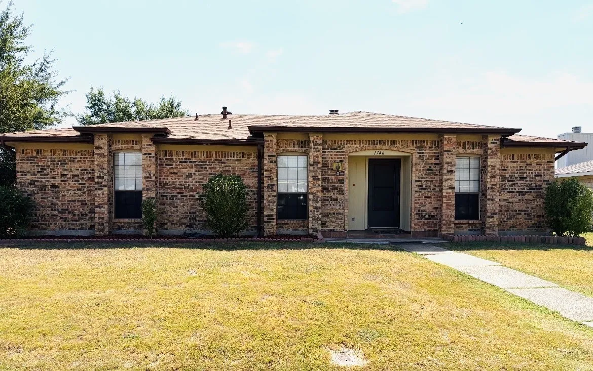 Brick exterior with a covered entry, multiple front-facing windows, and a concrete walkway