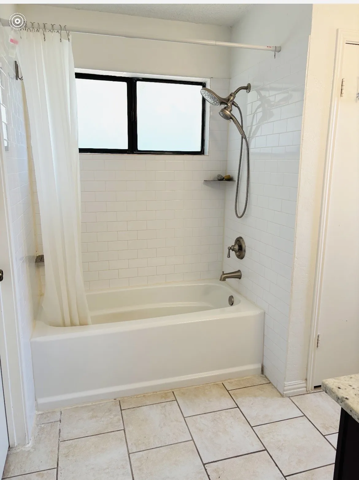 White subway tile surround with a built-in shelf, dual-head shower fixture, and a white bathtub