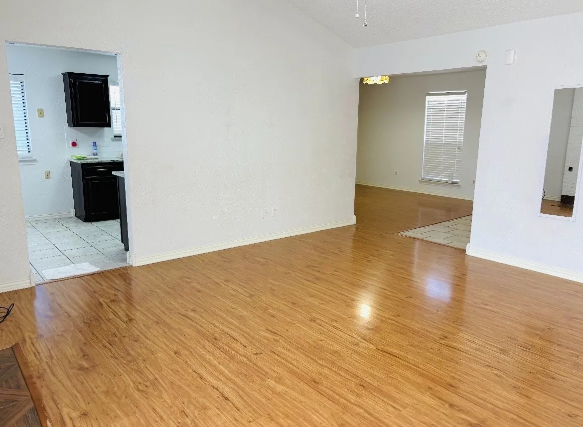 Wood-finish flooring throughout, vaulted ceiling, white walls, and a ceiling fan