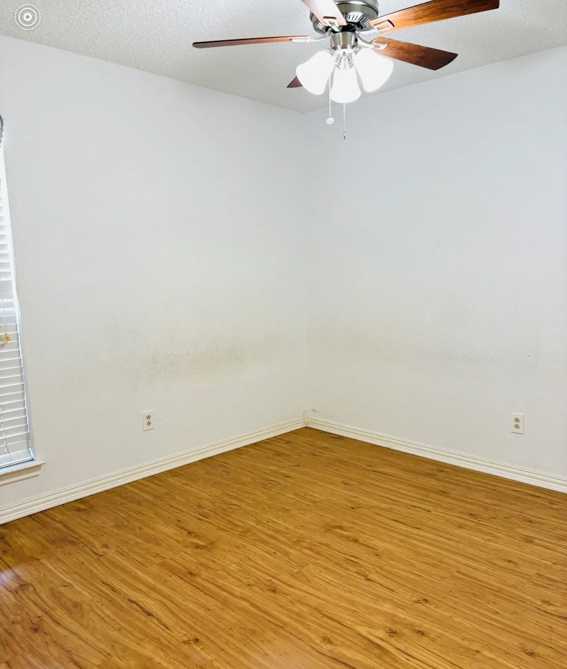 Wood-finish flooring, white walls, white window blinds, and a ceiling fan with integrated lighting