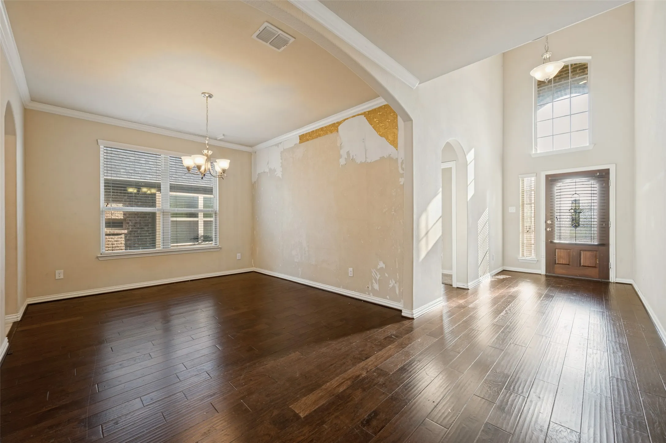 Wood-finish flooring throughout, with a double-height entryway featuring an arched doorway and transom window