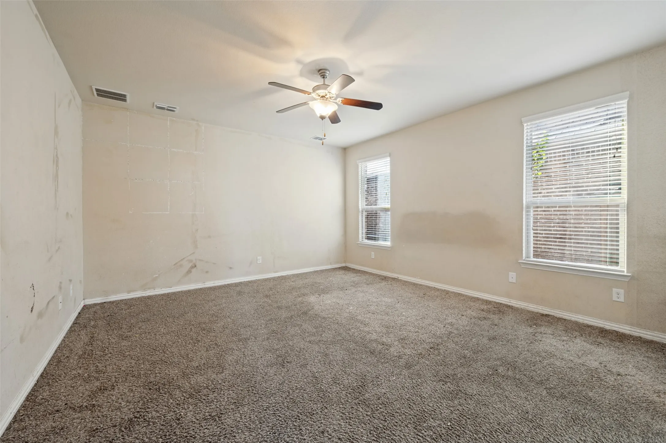Carpeted room featuring multiple windows with blinds and a ceiling fan with integrated lighting