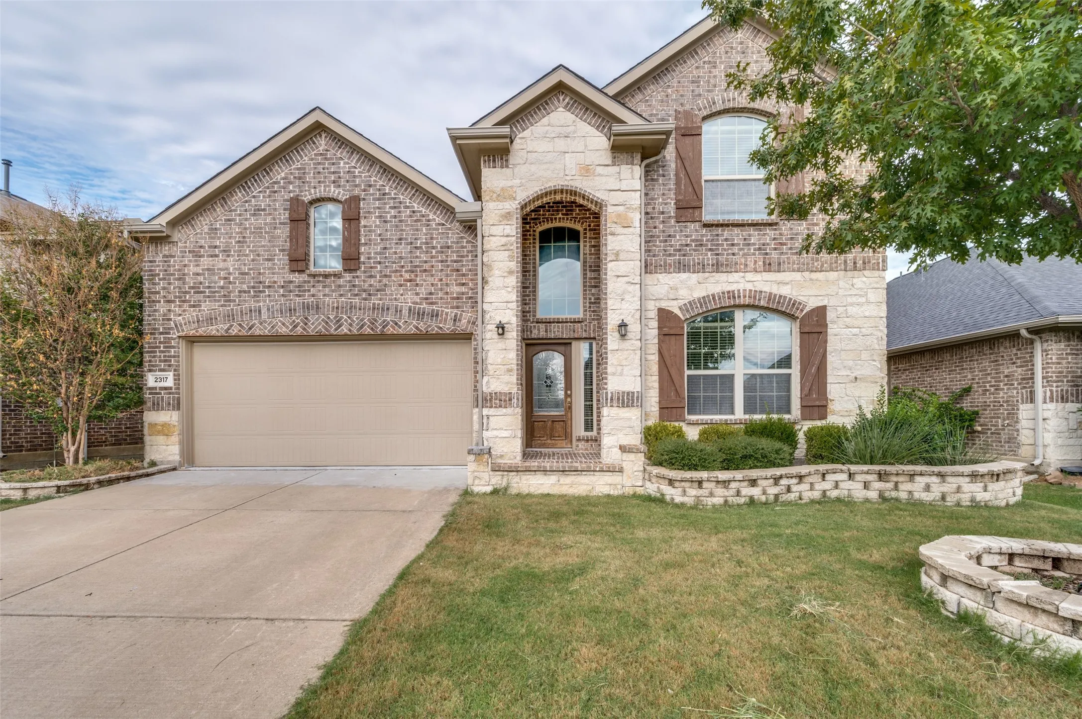 Brick and stone facade with arched windows, decorative shutters, and a prominent front entry