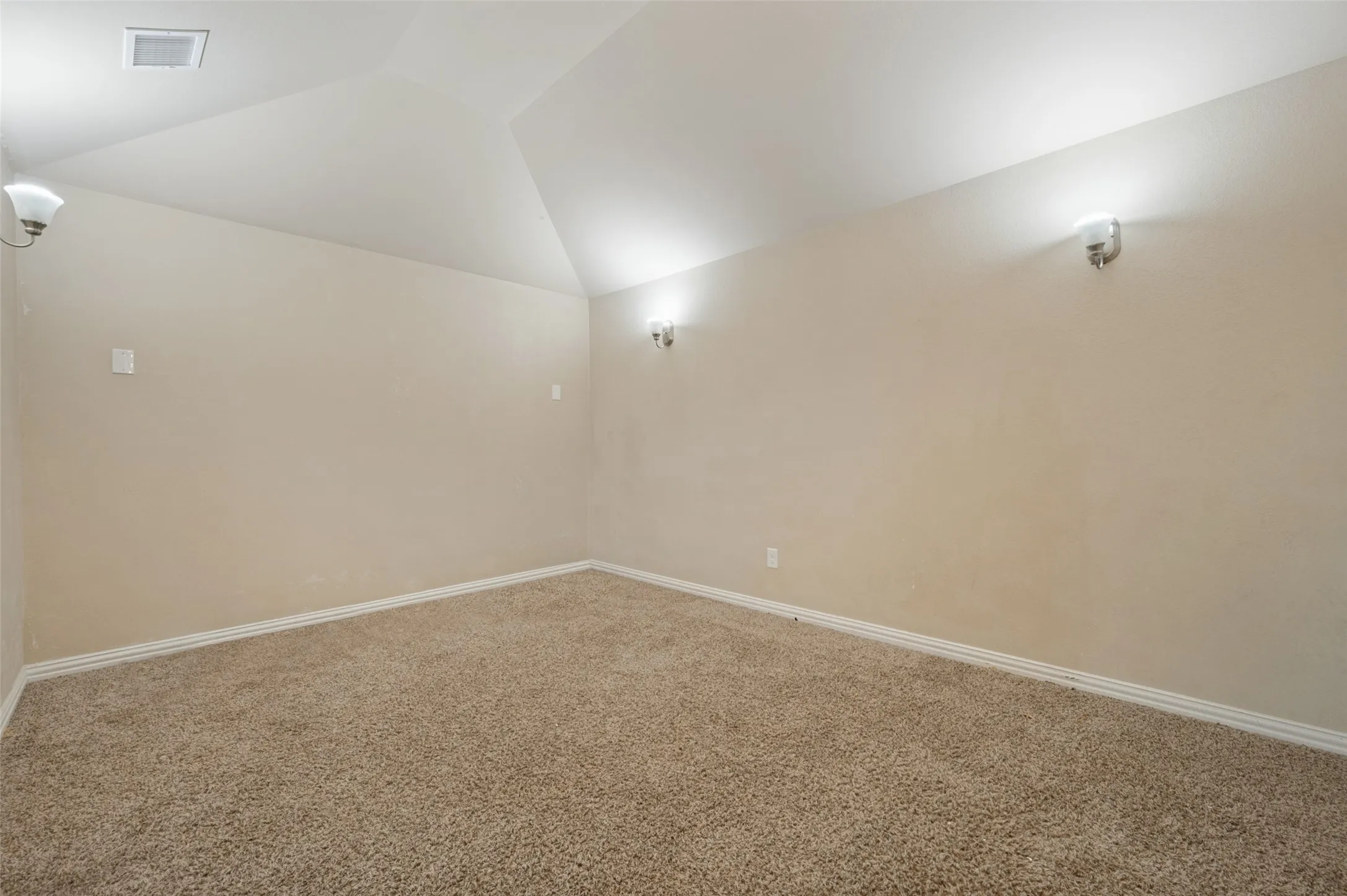 Sloped ceiling design with flush-mounted lighting and wall sconces