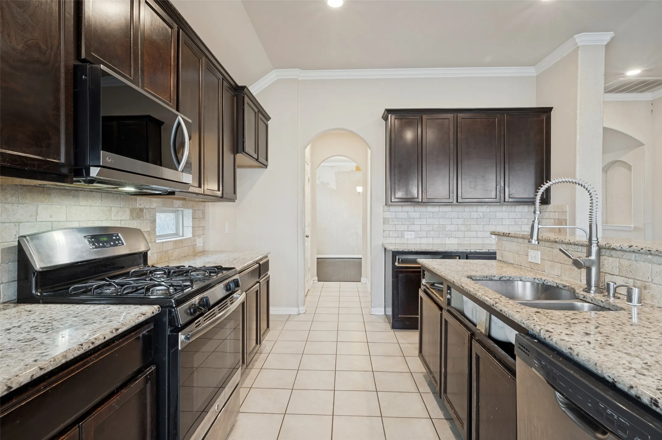 Kitchen featuring dark wood cabinetry, light-colored granite countertops, and stainless steel appliances