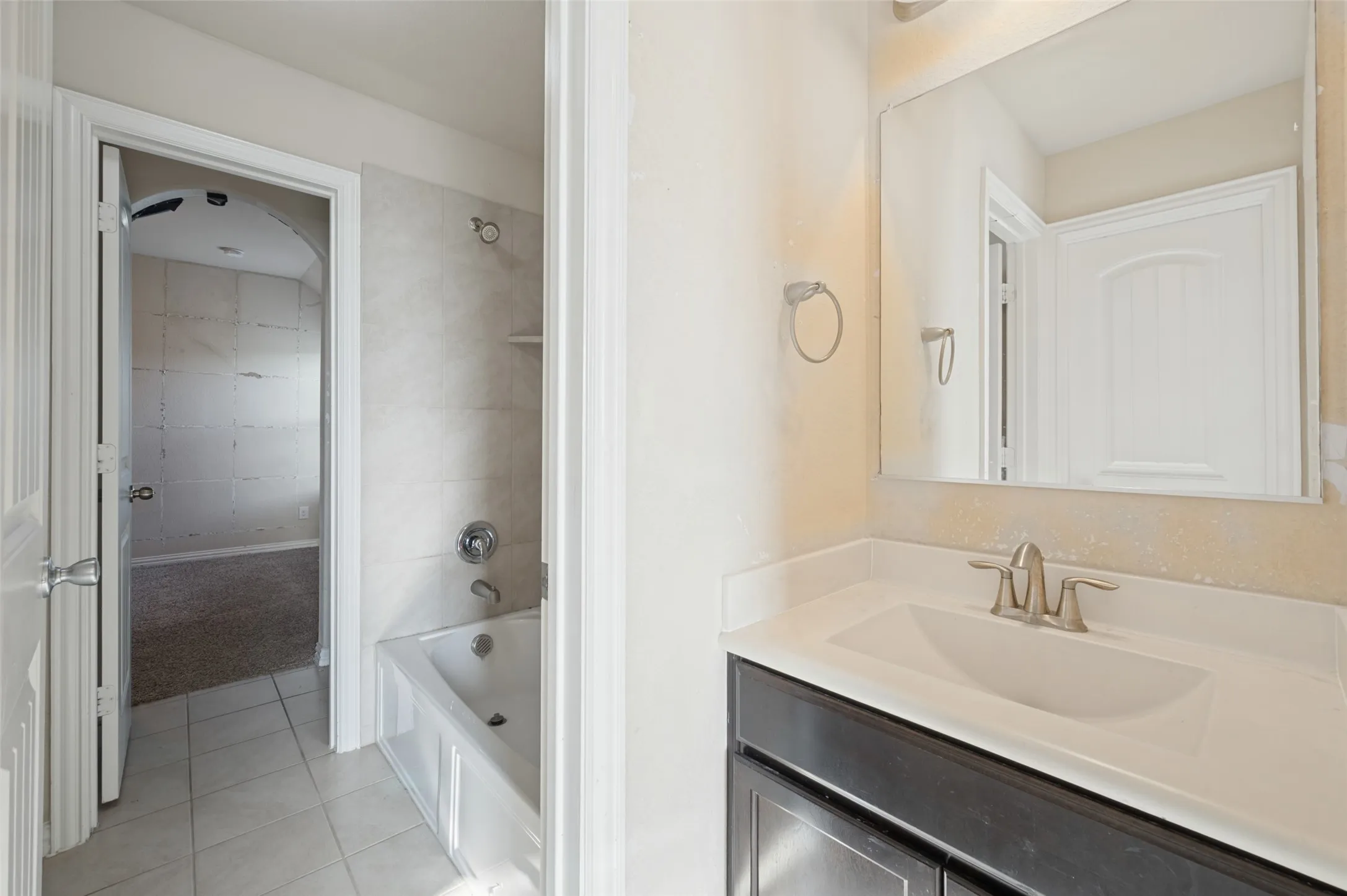 White vanity with a single basin sink, brushed nickel faucet, and a large mirror