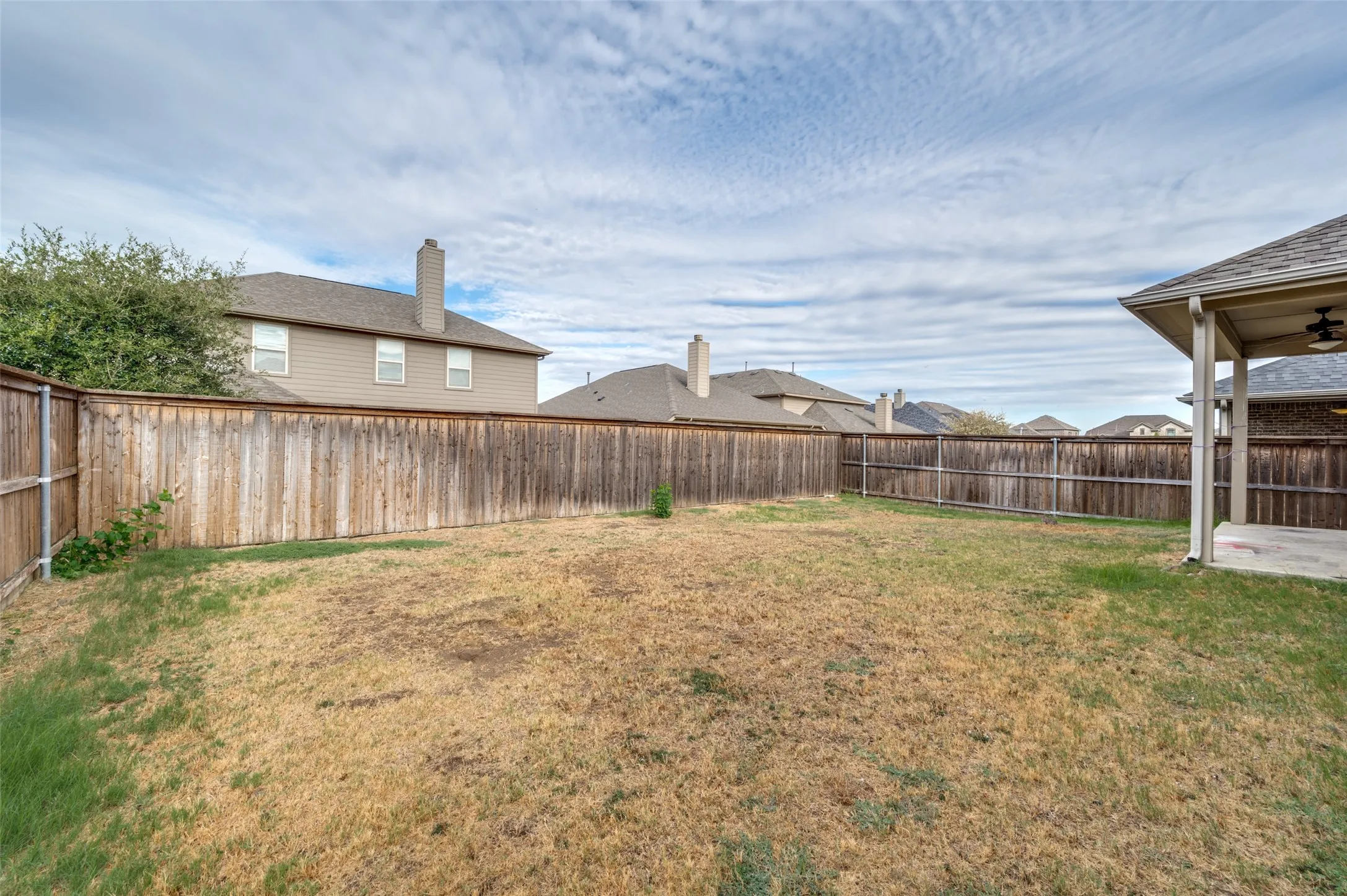 Expansive backyard with wood fencing and a covered patio area