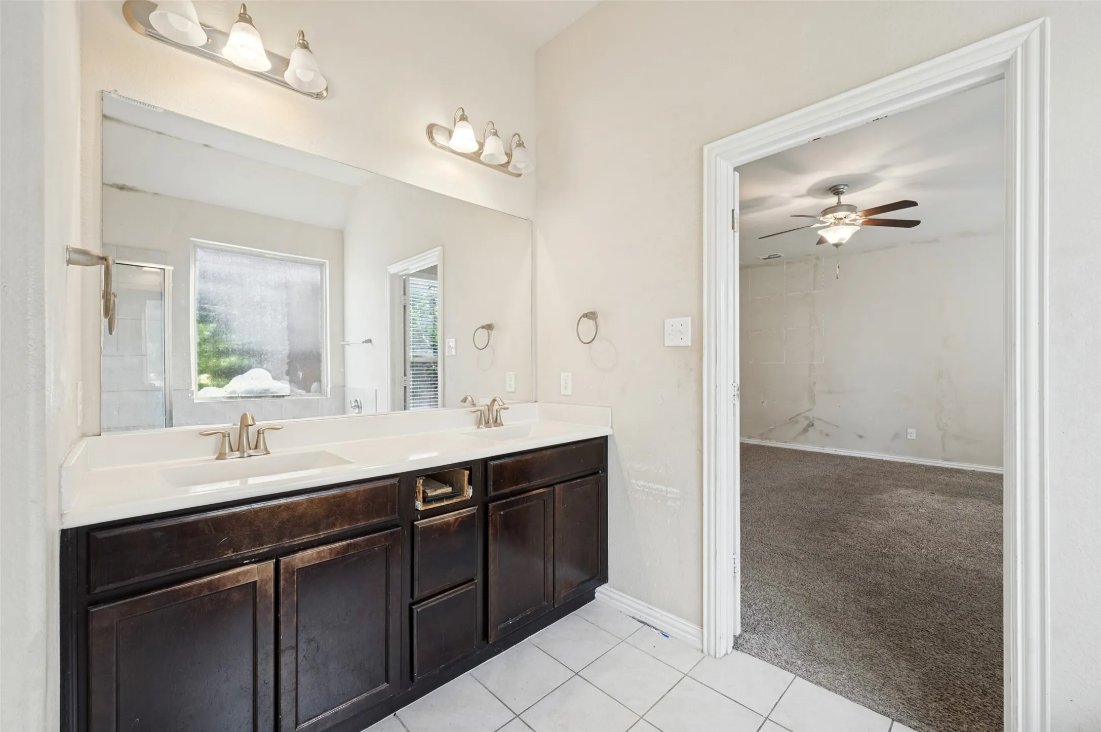 Double vanity with undermount sinks, bronze-finish fixtures, and a large wall-mounted mirror