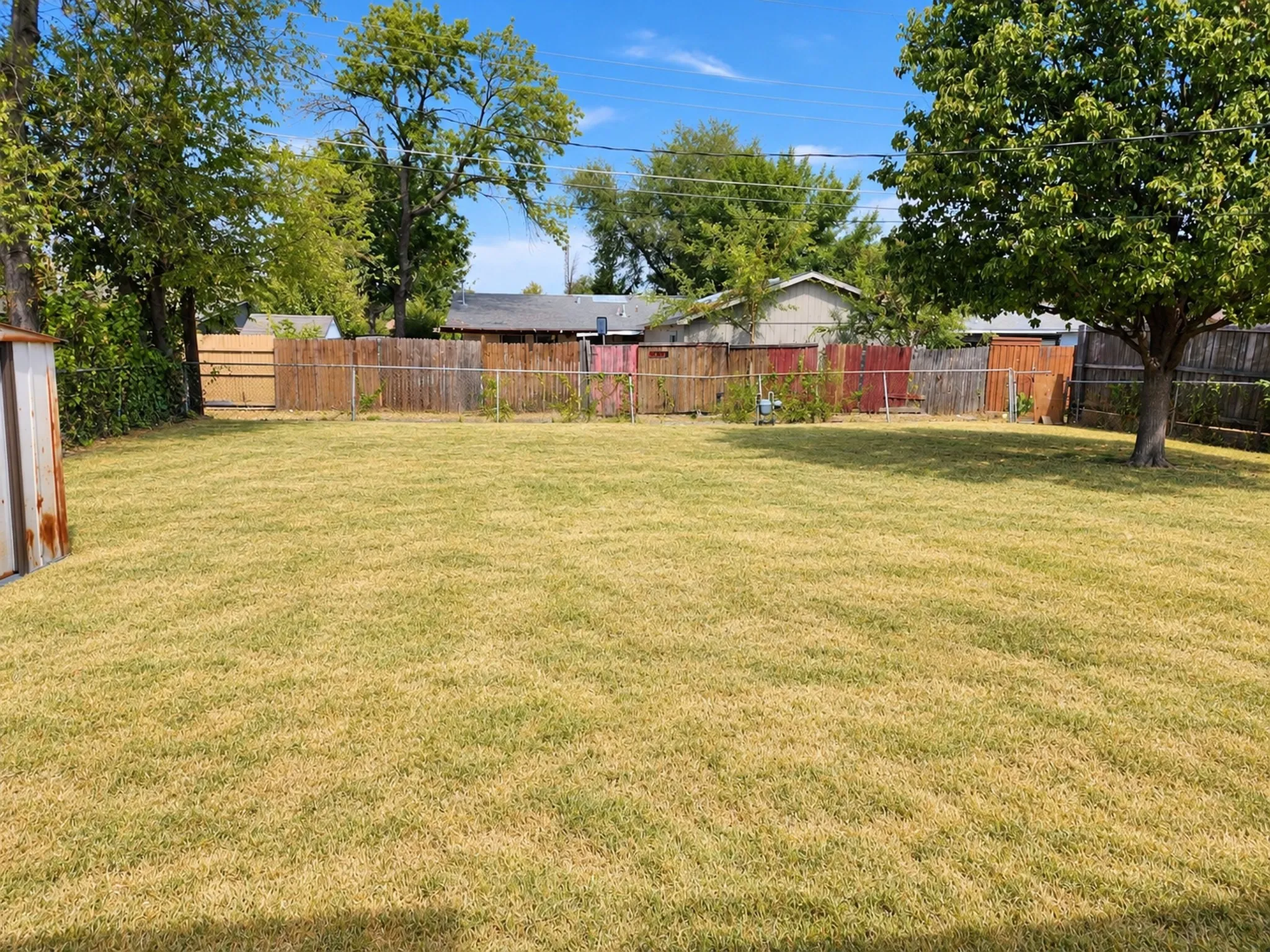 Expansive grass area, mature shade trees, and perimeter fencing