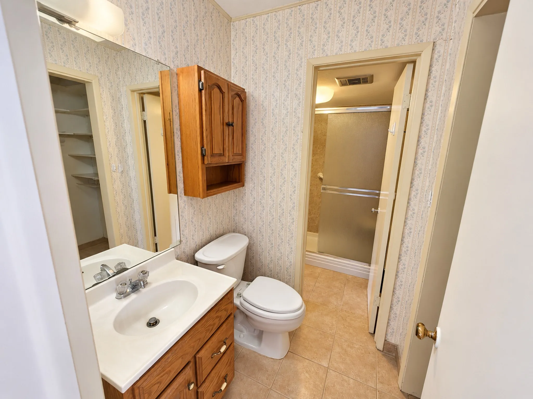 Bathroom vanity with wood-finish cabinetry, integrated sink, and an overhead mirror