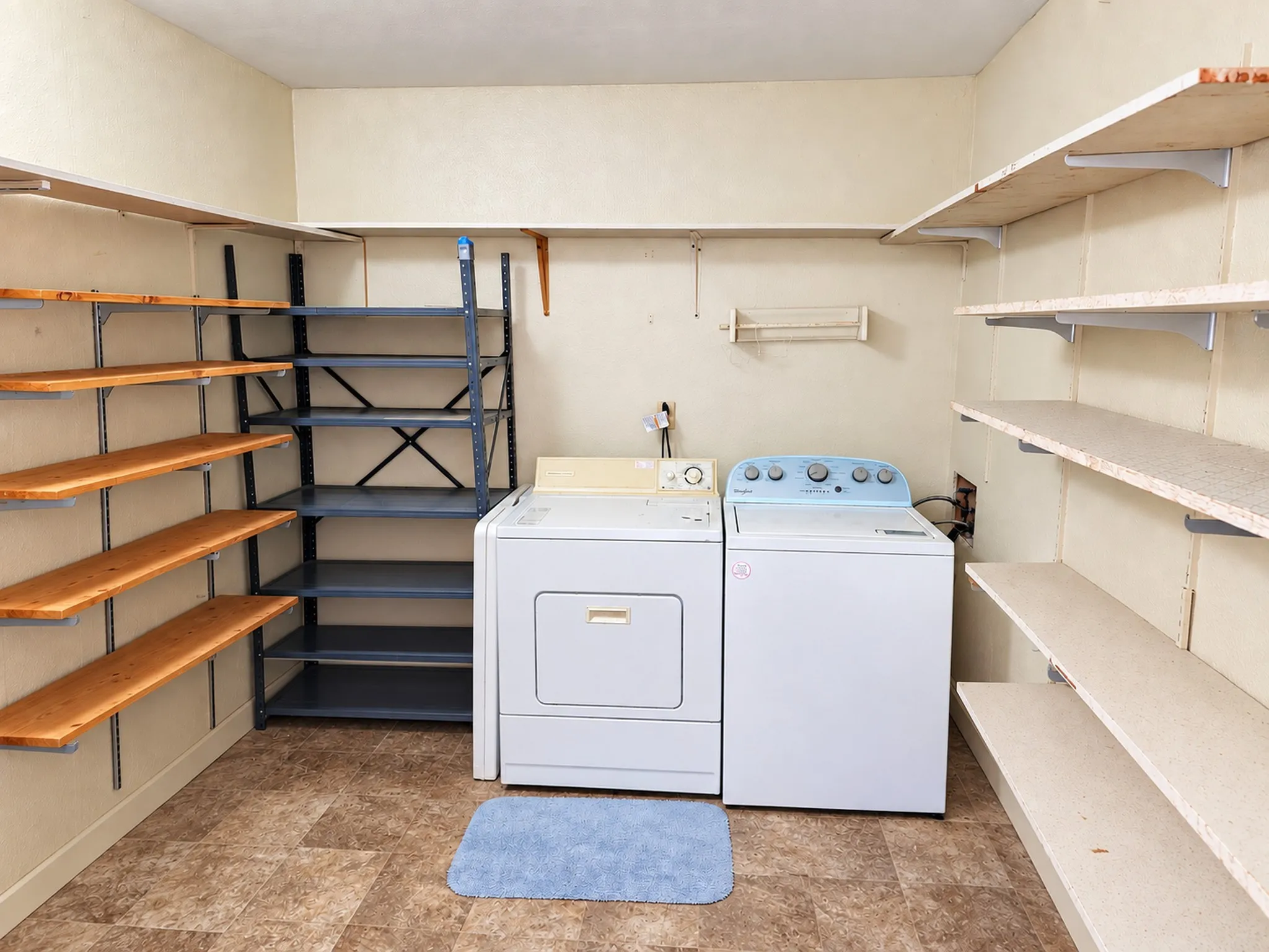 Dedicated utility area featuring a washer and dryer, extensive wall-mounted shelving, and durable flooring