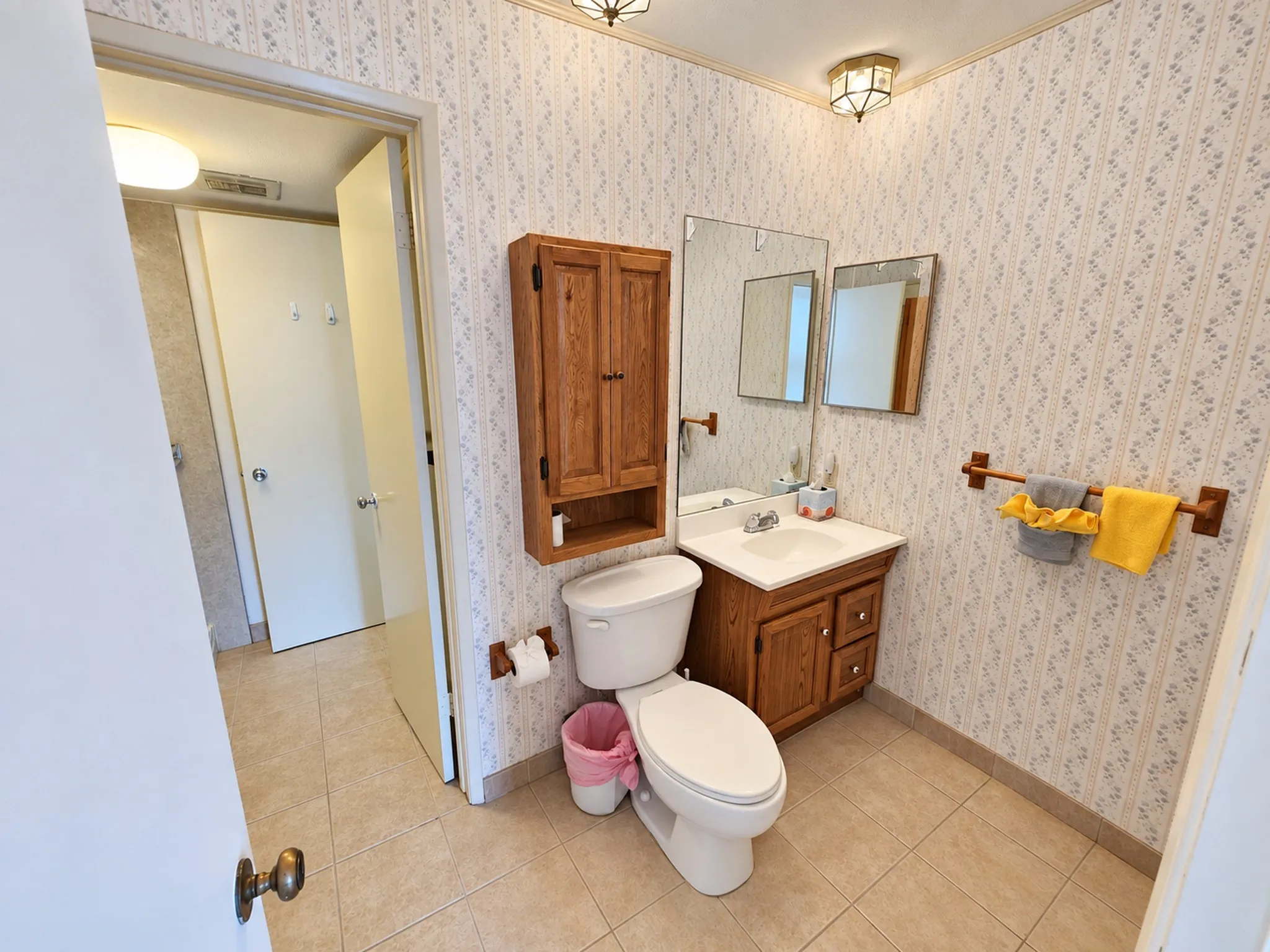 Bathroom featuring a vanity with a white countertop and wood-finish cabinetry, a wall-mounted medicine cabinet, and tiled flooring
