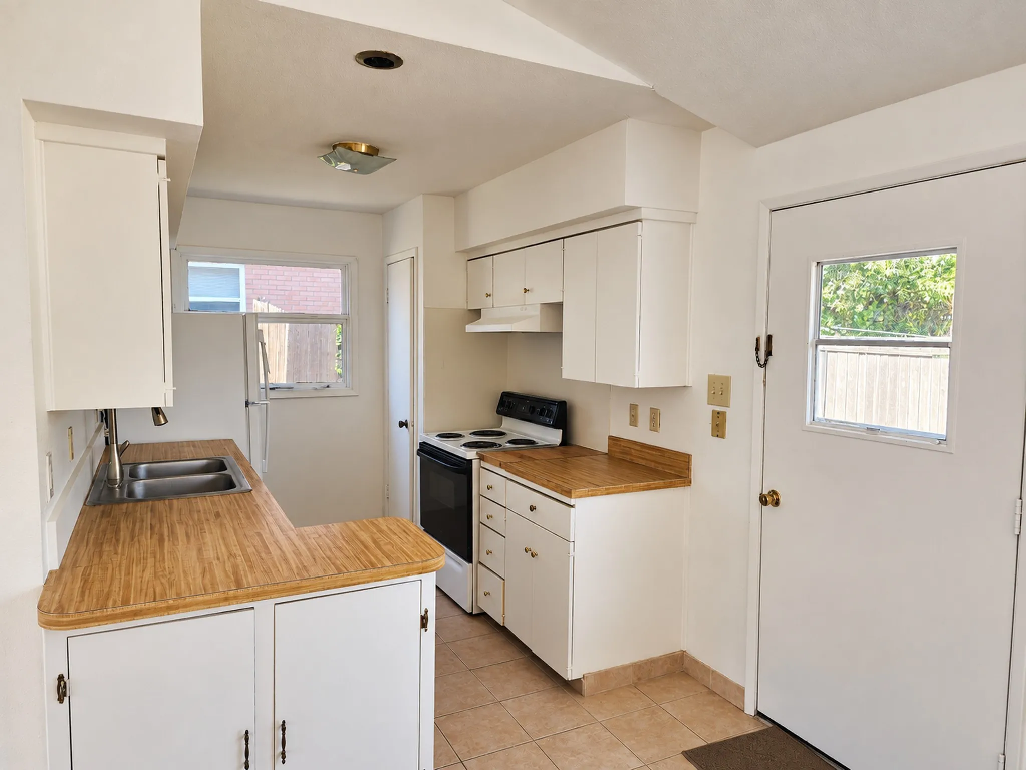 Kitchen featuring white cabinetry, wood-finish countertops, stainless steel double-basin sink, and a white electric range