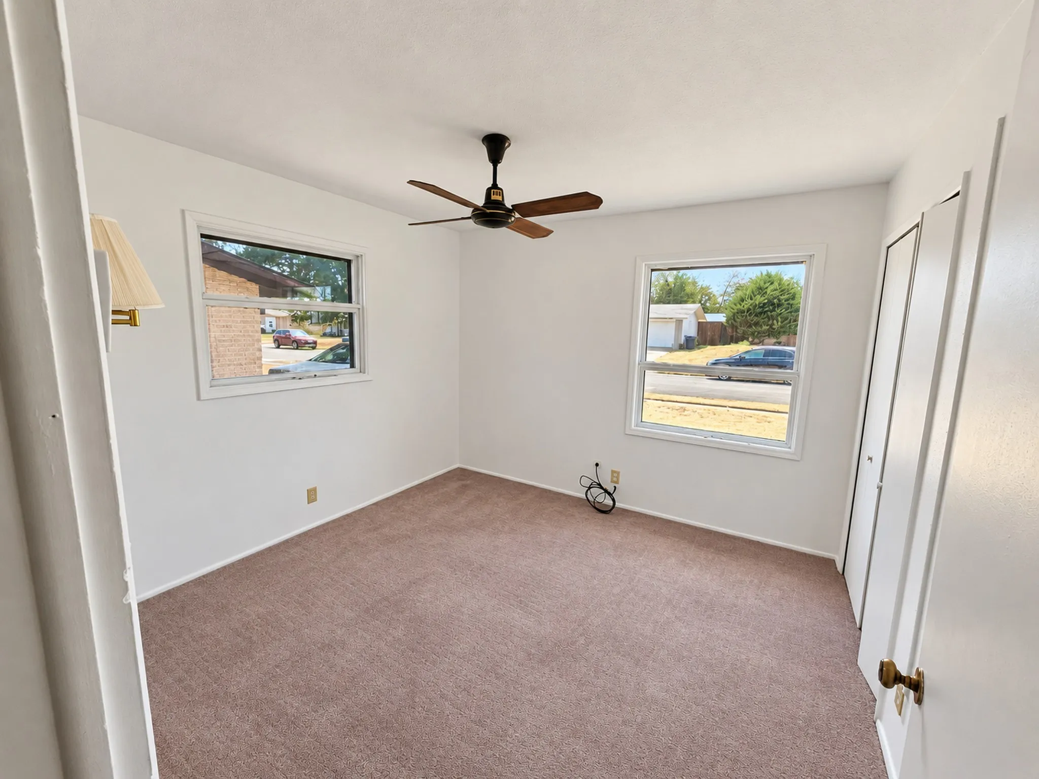 Wall-to-wall carpeting, two windows, and a ceiling fan with integrated lighting