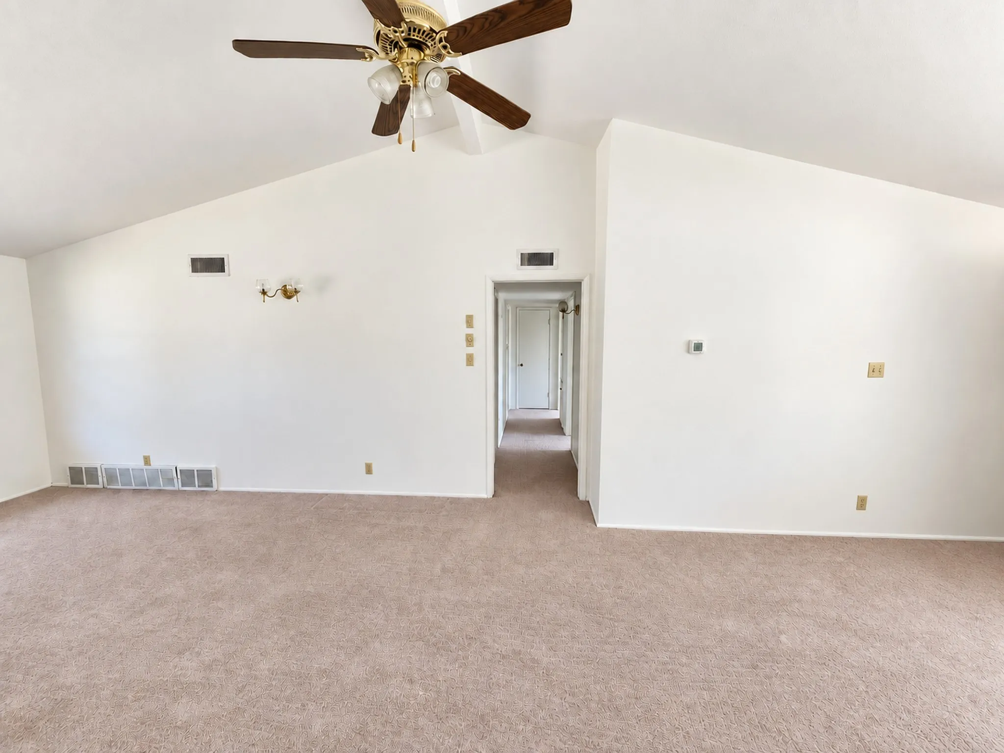Vaulted ceiling with a ceiling fan, wall sconce lighting, and a neutral carpeted​​‌​​​​‌​​‌‌​‌‌​​​‌‌​‌​‌​‌​​​‌​​ floor