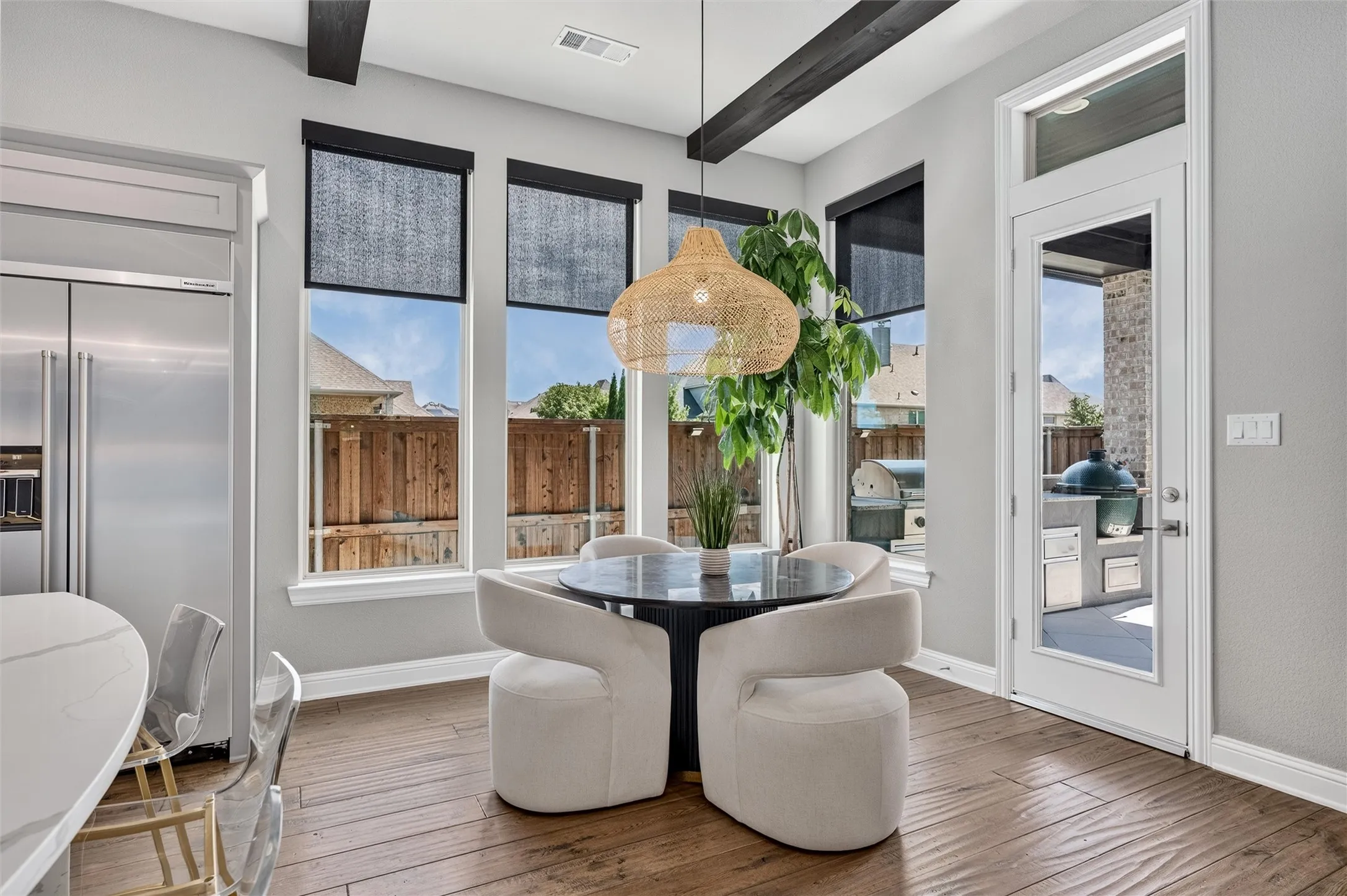 Wood-finish flooring, exposed ceiling beams, white trim, and a glass-paneled door