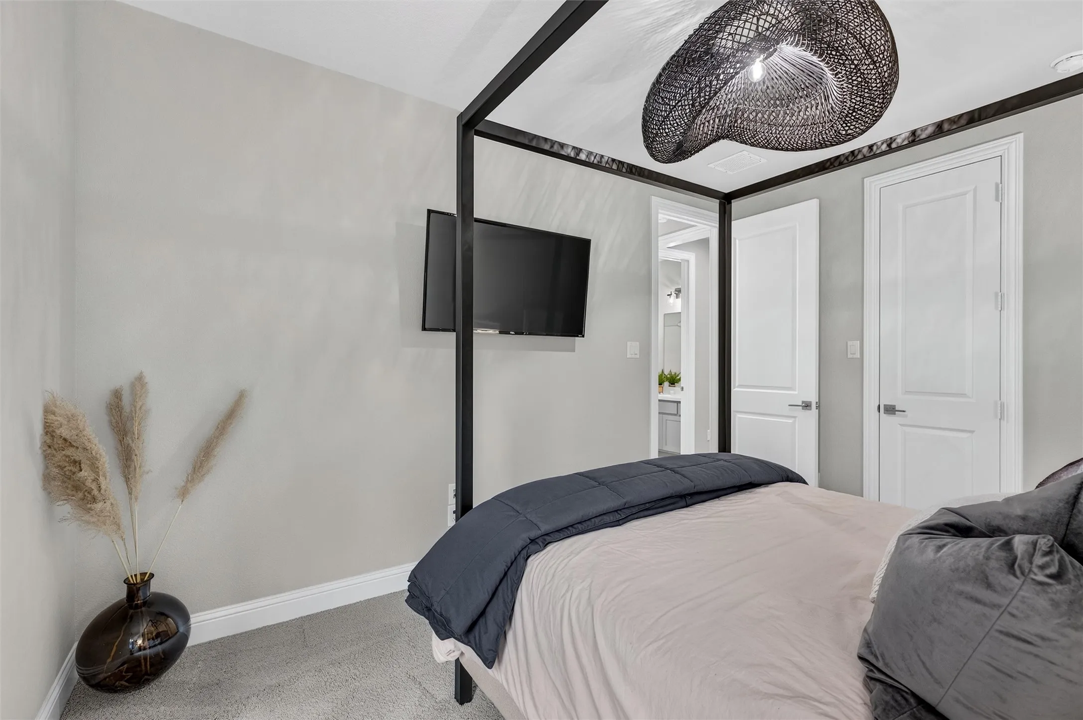 Wall-mounted television, textured ceiling light fixture, neutral wall paint, and white paneled doors with brushed nickel hardware