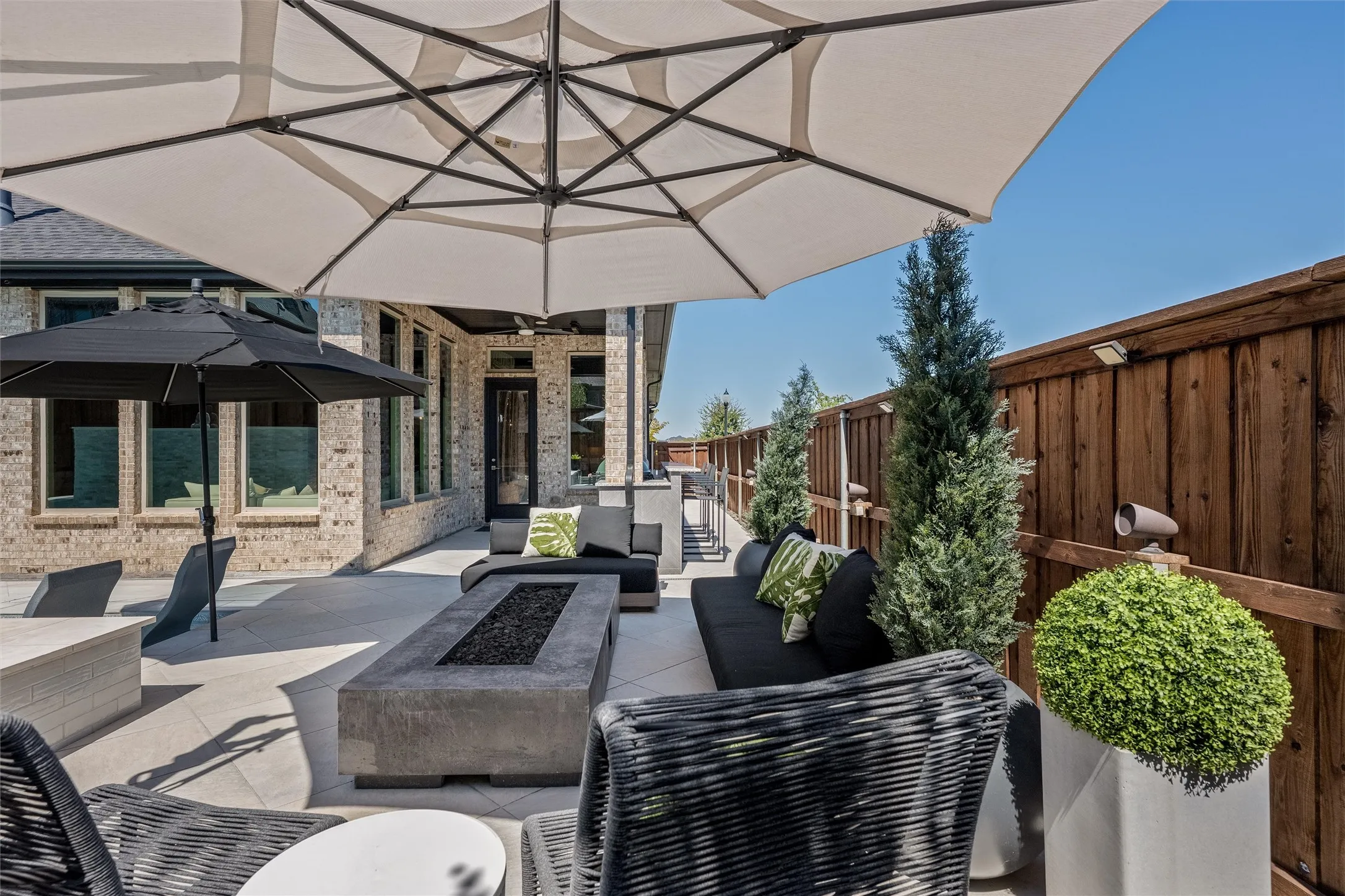 Expansive outdoor patio featuring a concrete fire pit, solid wood privacy fence, and brick exterior