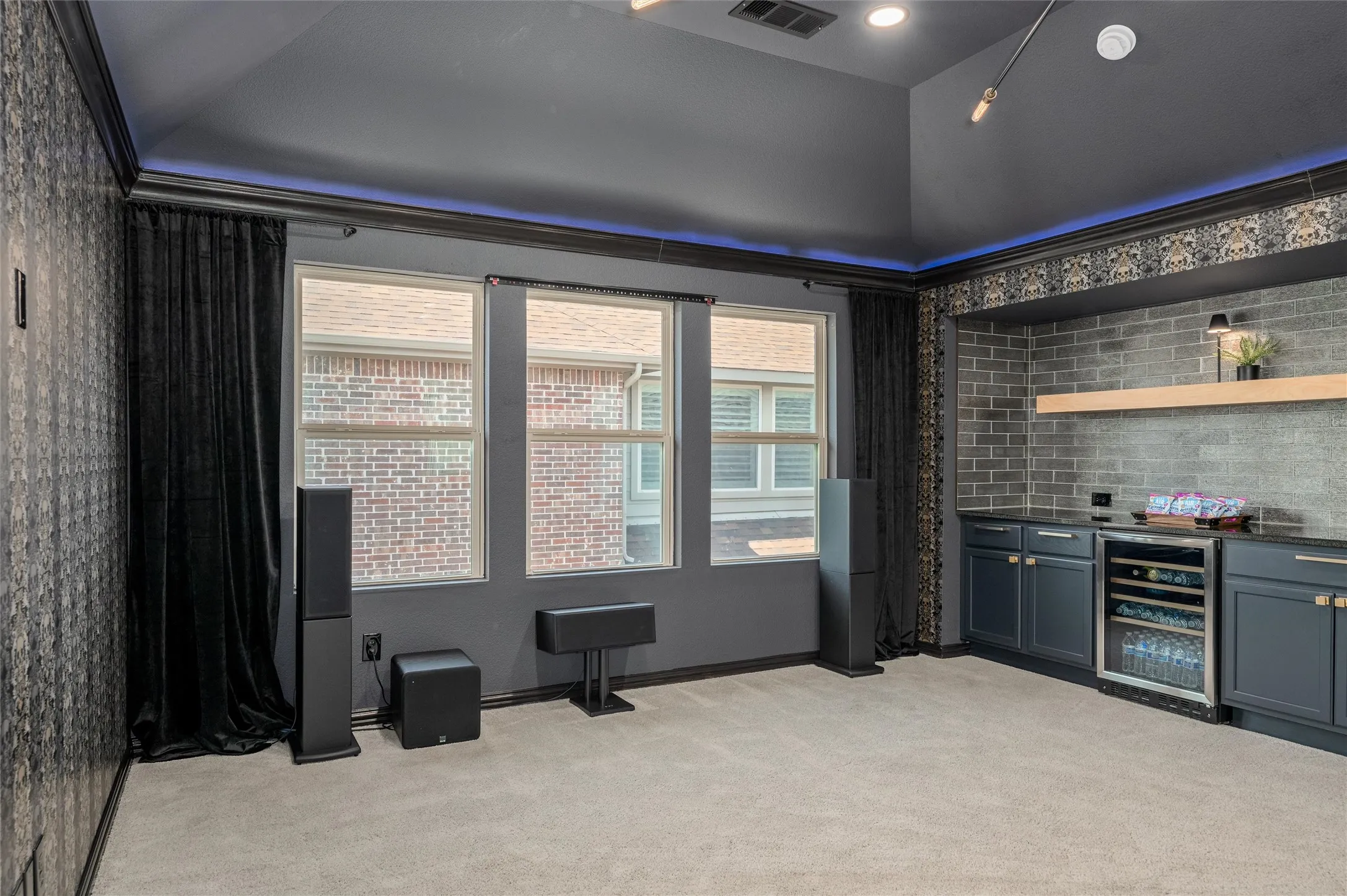 Vaulted ceiling with recessed lighting, integrated entertainment bar with beverage cooler, gray brick-style accent wall, and built-in shelving