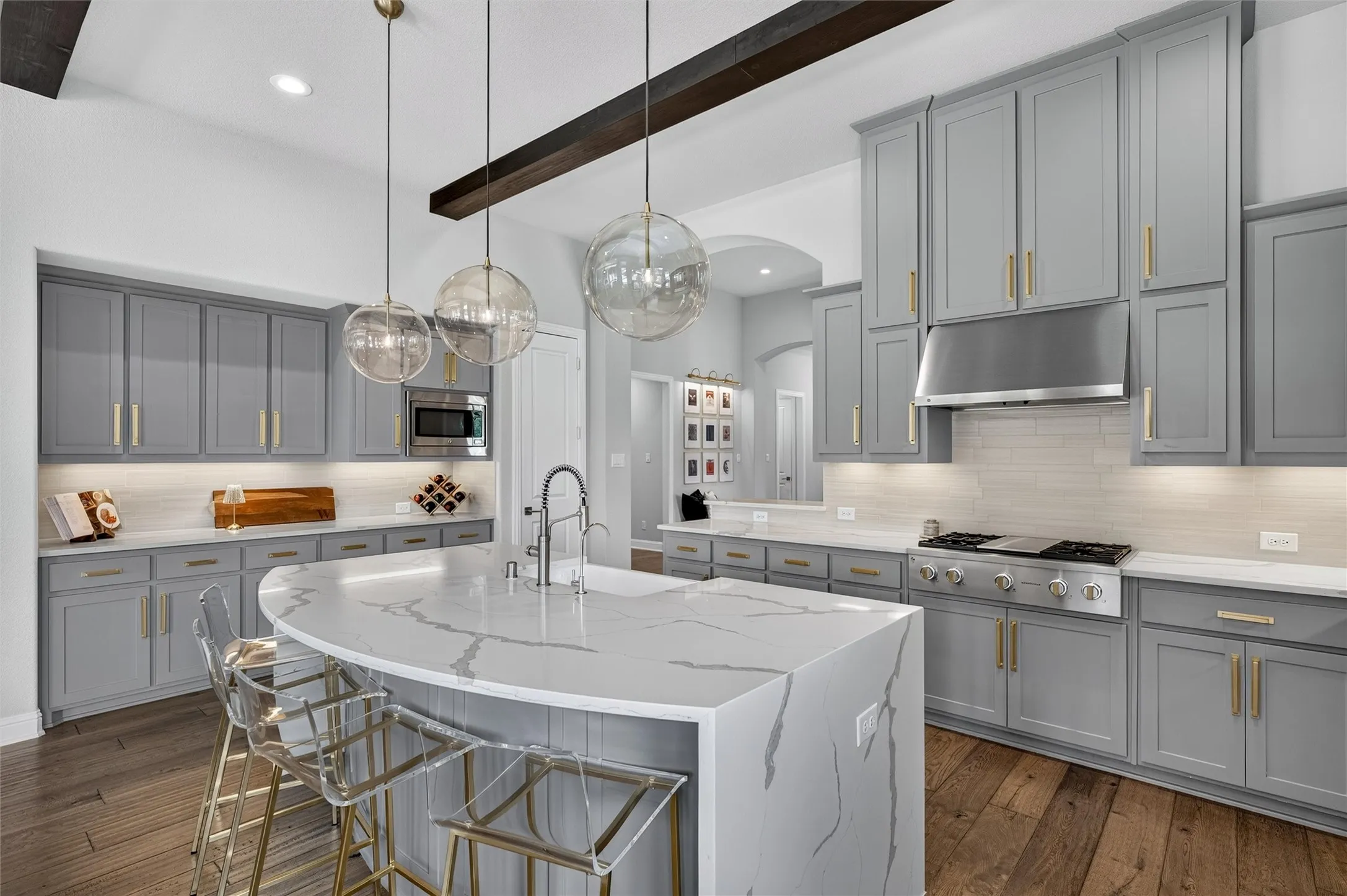 Spacious kitchen featuring gray cabinetry, wood-finish flooring, white countertops with veining, and a stainless steel range with matching hood