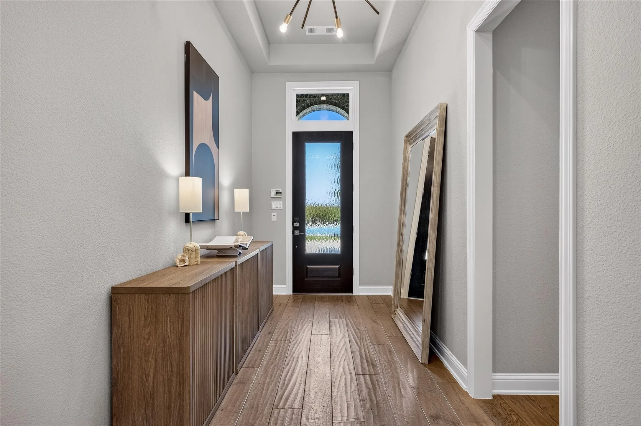 Entryway featuring wood-finish flooring, a dark entry door with decorative glass, and a decorative arched transom window