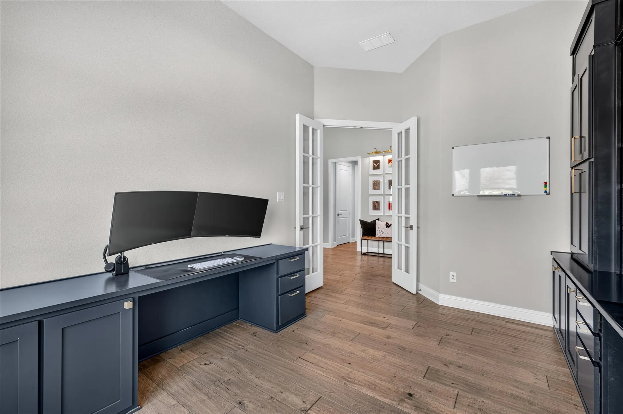 Wood-finish flooring, built-in desk cabinetry, built-in storage unit, and French doors