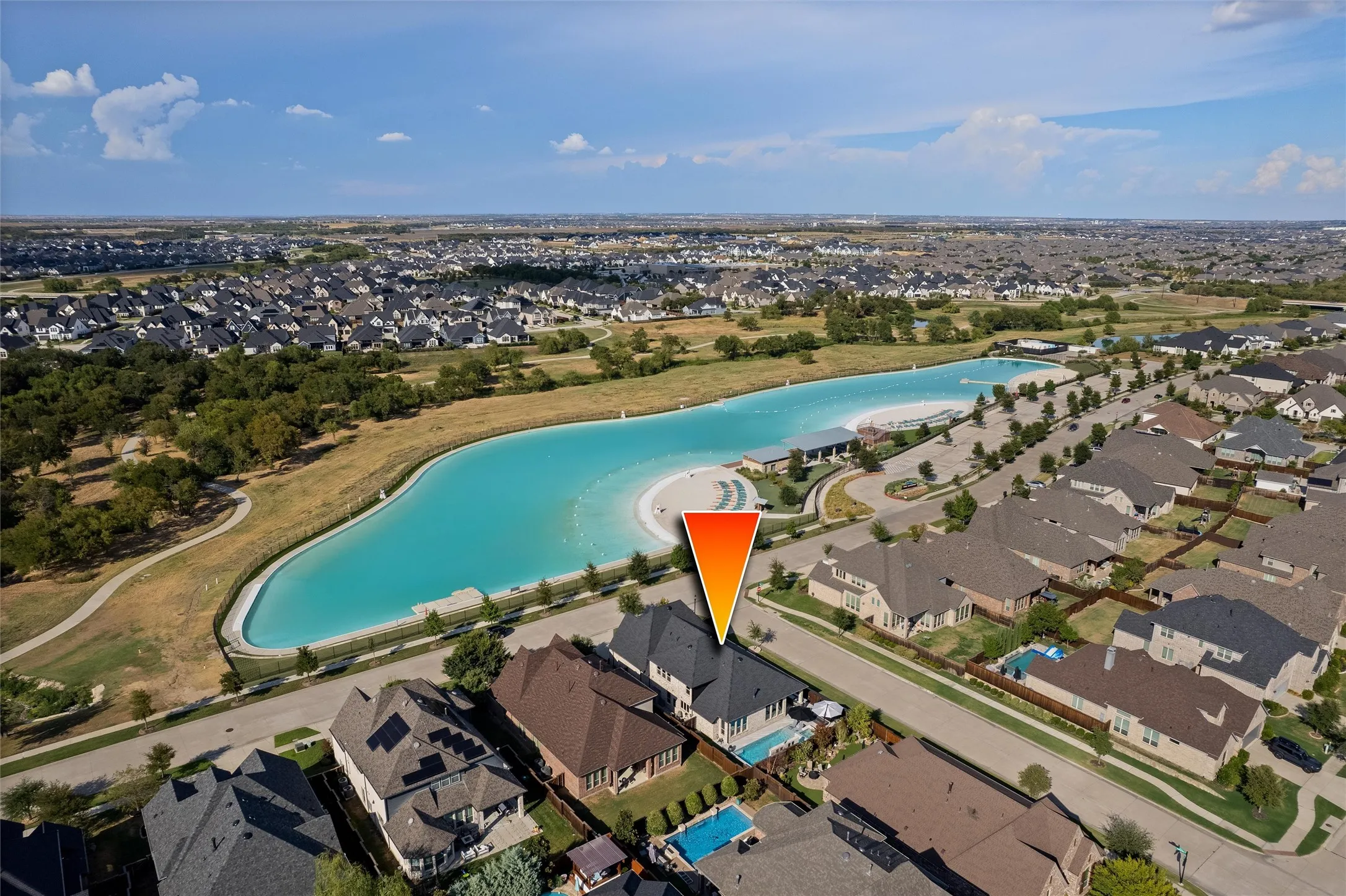 Residential property with a private swimming pool, surrounded by a suburban neighborhood, with a large aquatic amenity featuring a beach entry
