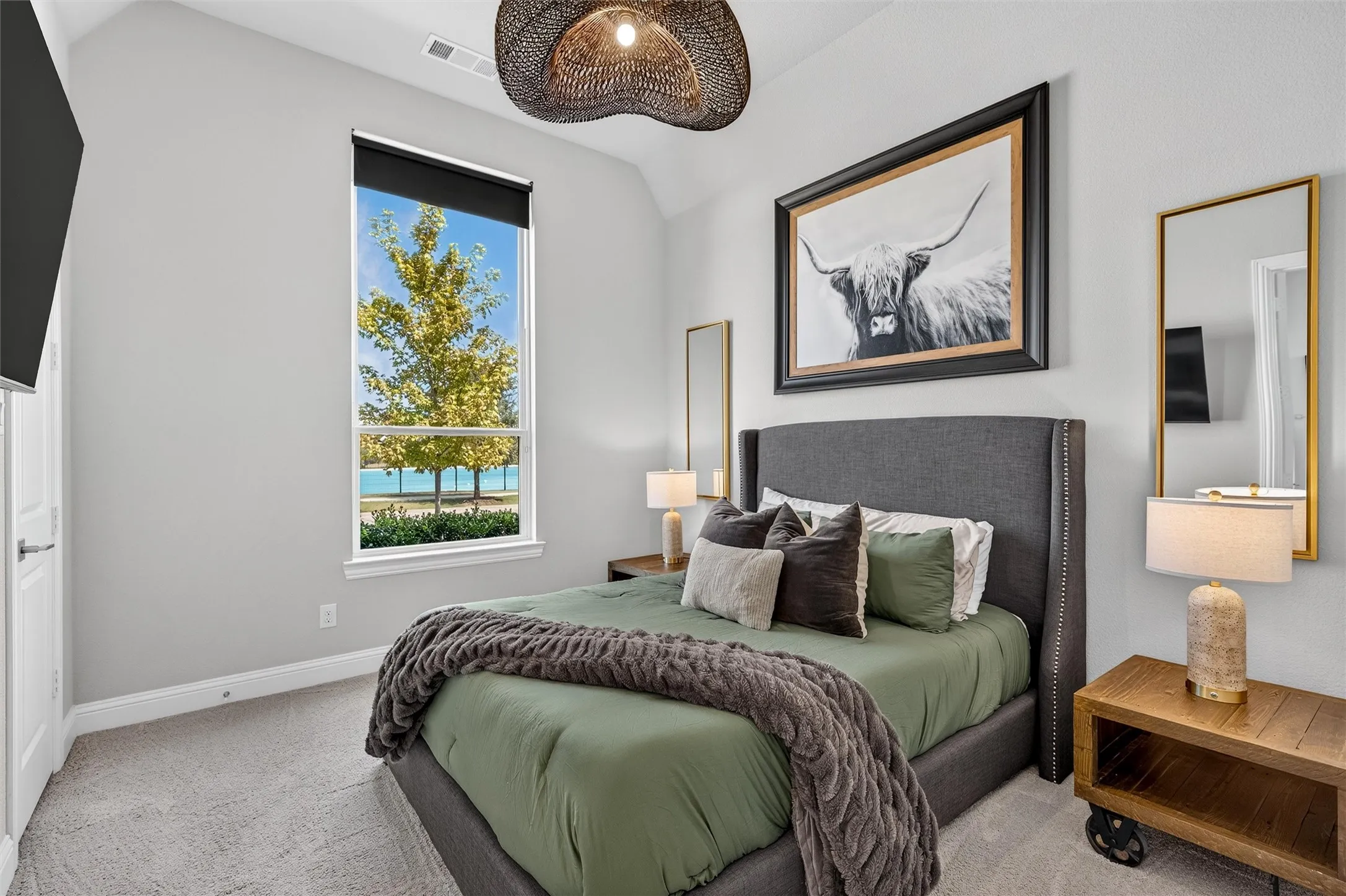Room featuring a high vaulted ceiling, single window with a roller shade, light-toned carpeting, and a white paneled door