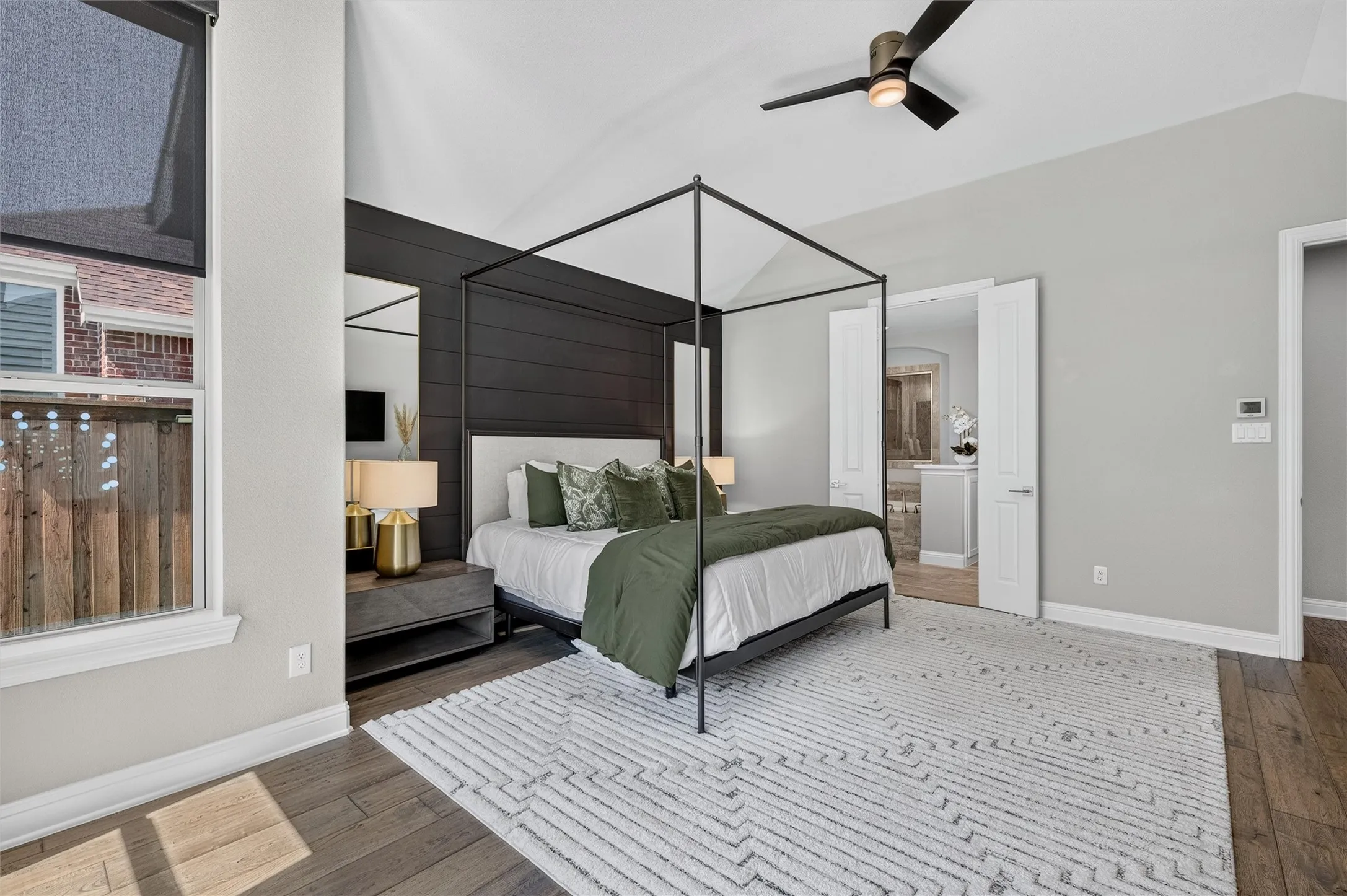 Vaulted ceiling with a ceiling fan, accent wall with horizontal paneling, wood-finish flooring, and double doors