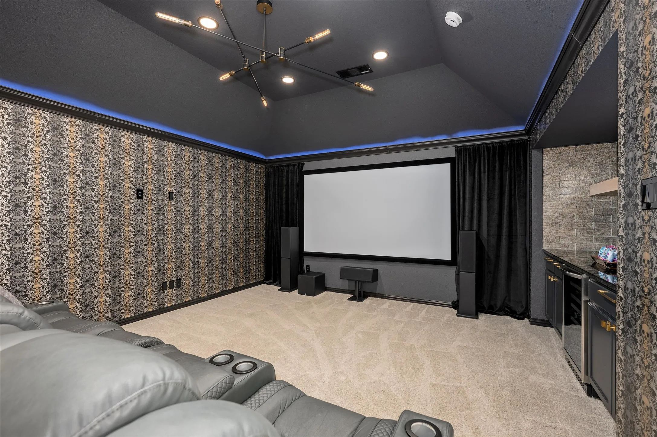 Dedicated media room featuring a large projection screen, recessed lighting, and patterned wall coverings