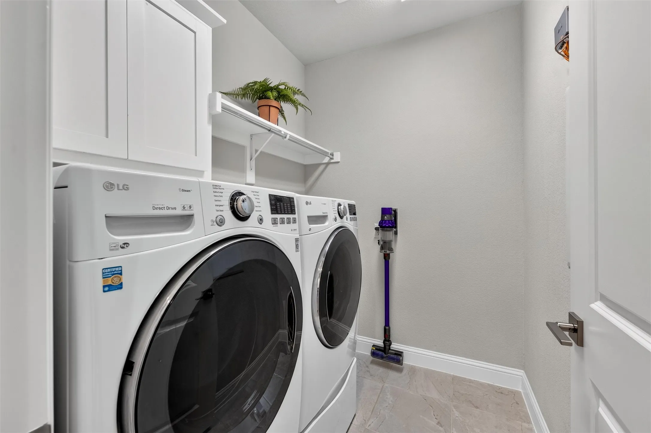 White shaker-style cabinetry, overhead shelving, and light-toned flooring