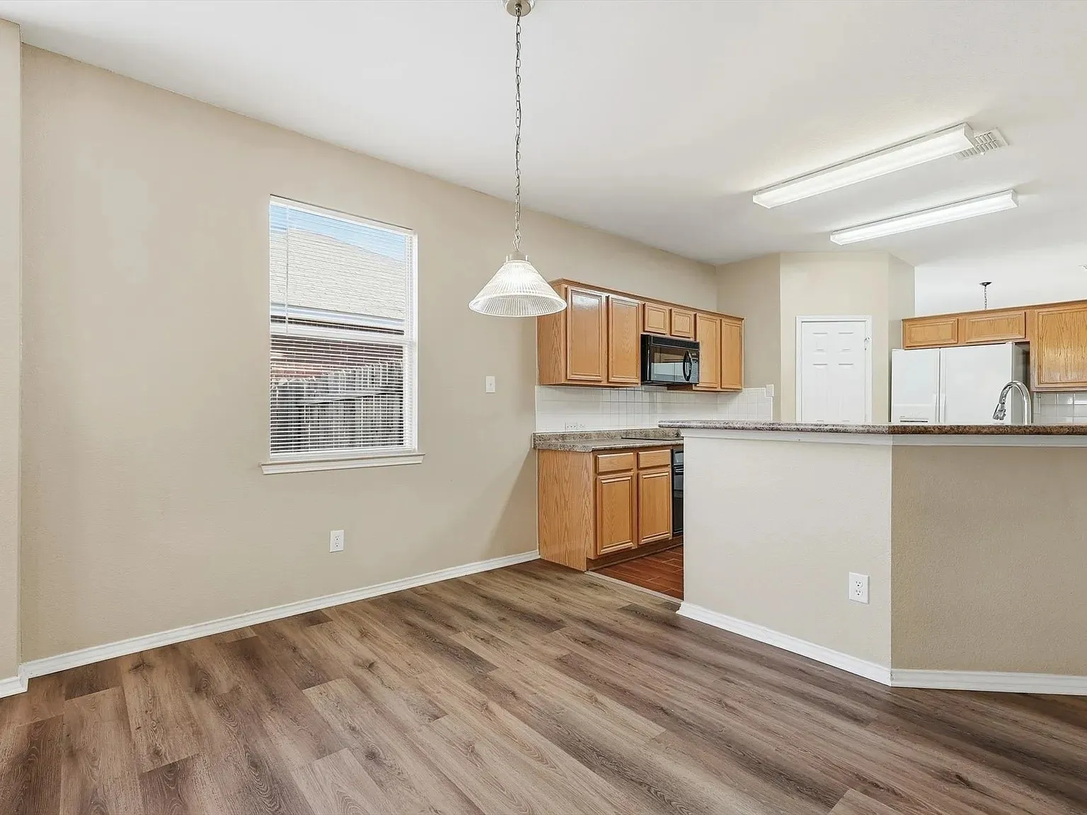 Dining area featuring wood-finish flooring and a contemporary pendant light fixture