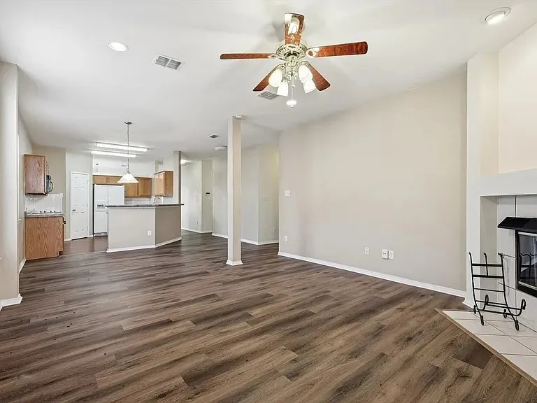 Spacious living area featuring wood-finish flooring, neutral wall tones, and a built-in fireplace