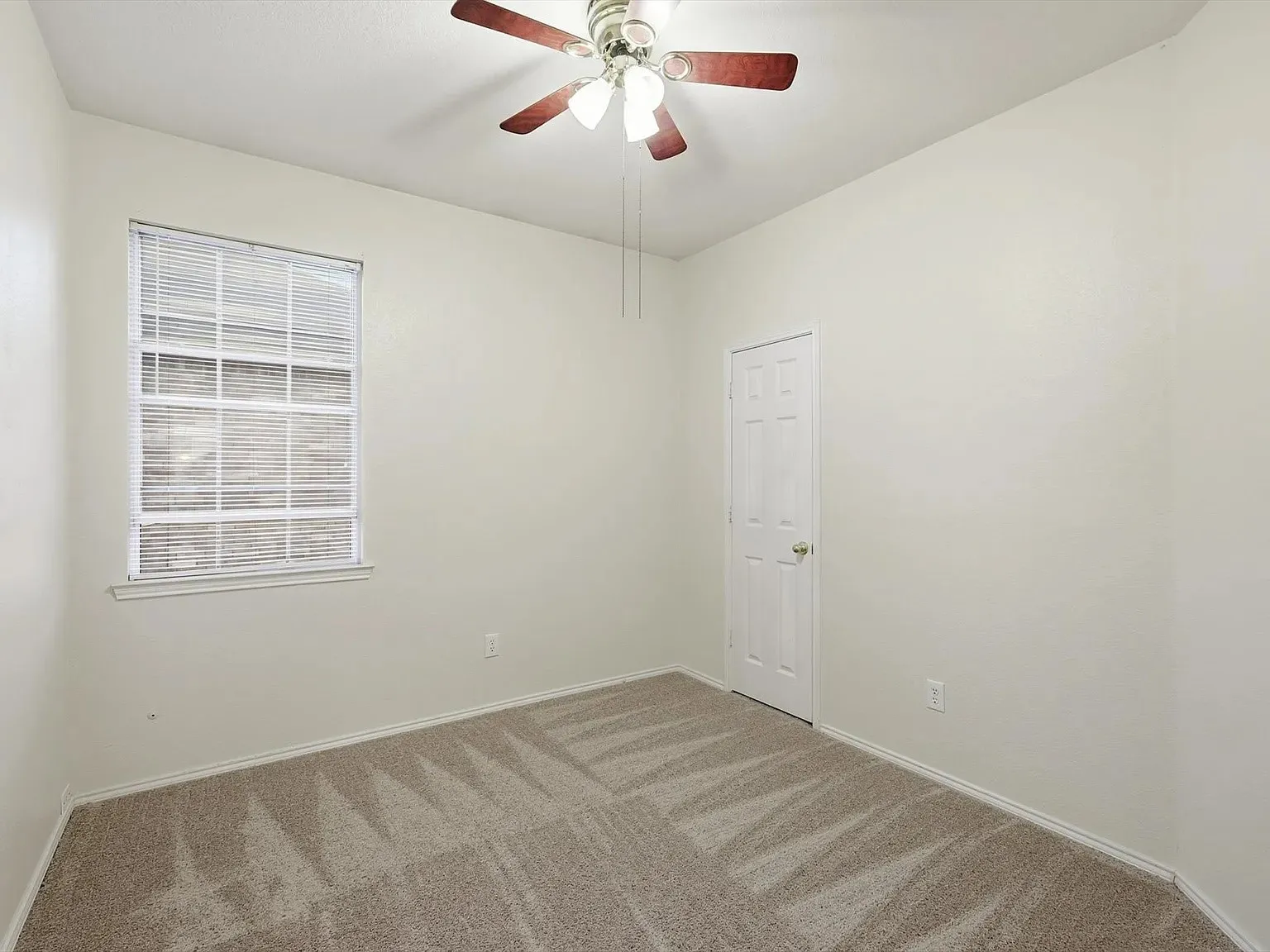 Carpeted room featuring a ceiling fan with integrated lighting, a window with horizontal blinds, and a paneled interior door