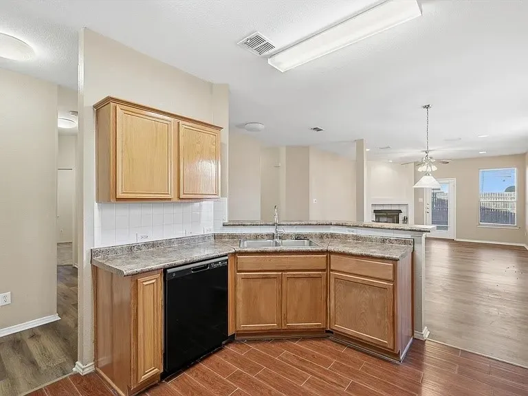 Kitchen featuring wood-finish cabinetry, a double basin sink, and a black dishwasher