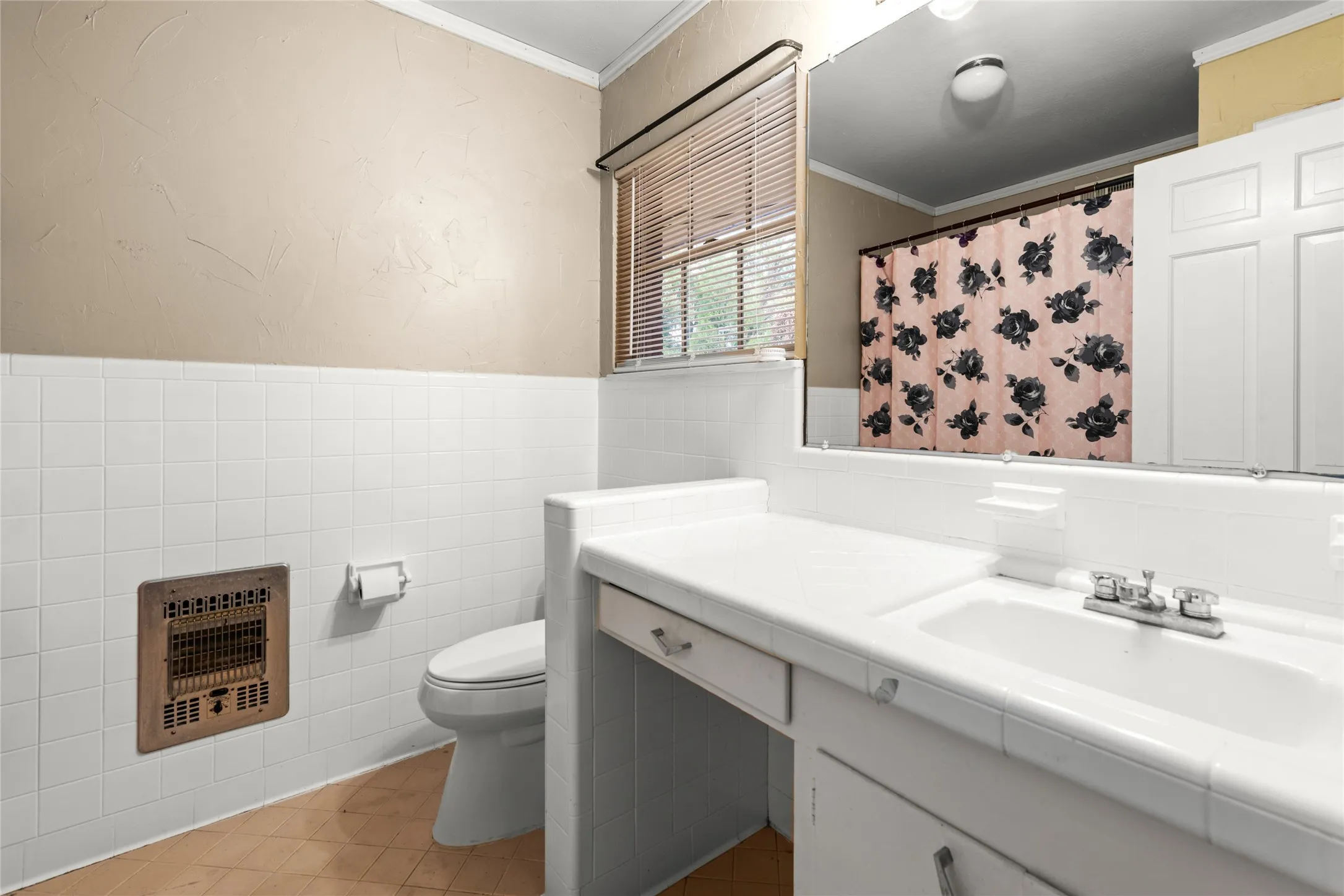 Bathroom featuring a built-in vanity with an integrated sink, white tiled walls, and a window with blinds