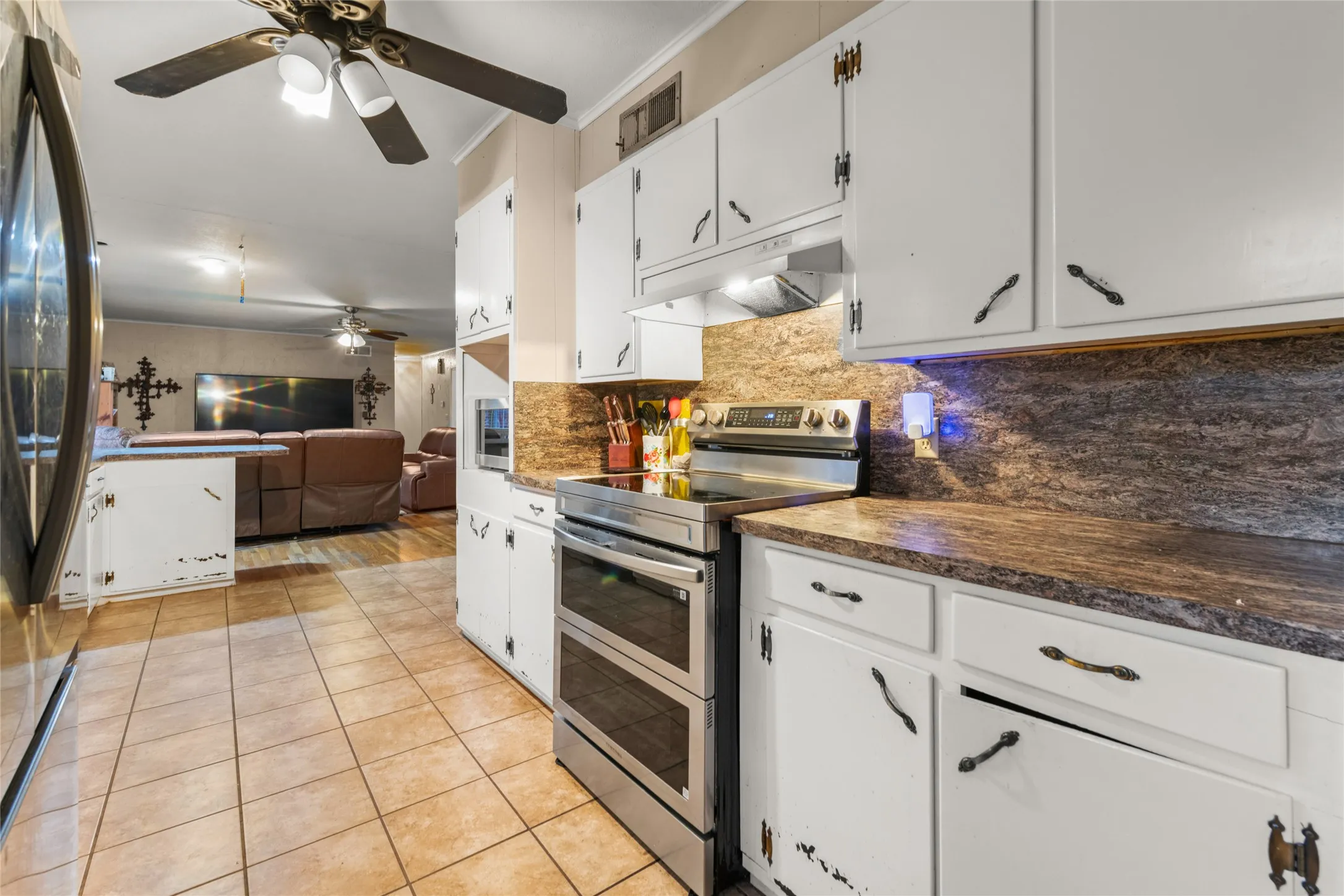 Kitchen featuring white cabinetry, dark countertops, tile flooring, and a stainless steel range with a double oven