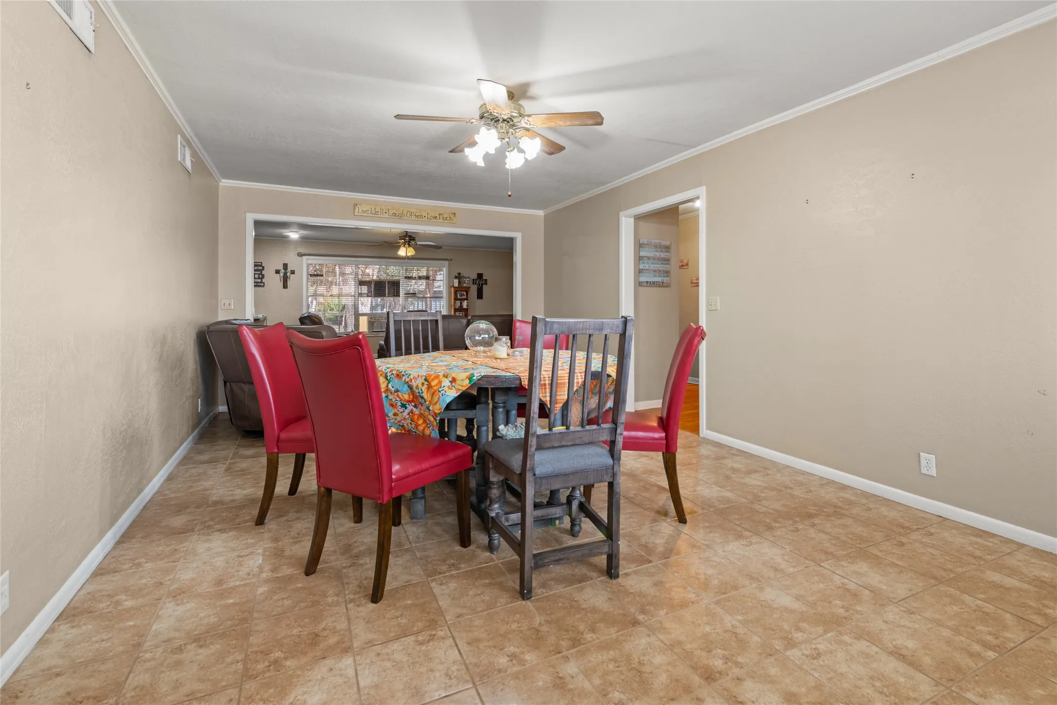 Tile flooring, crown molding, cased opening to additional living space, ceiling fan with light fixture