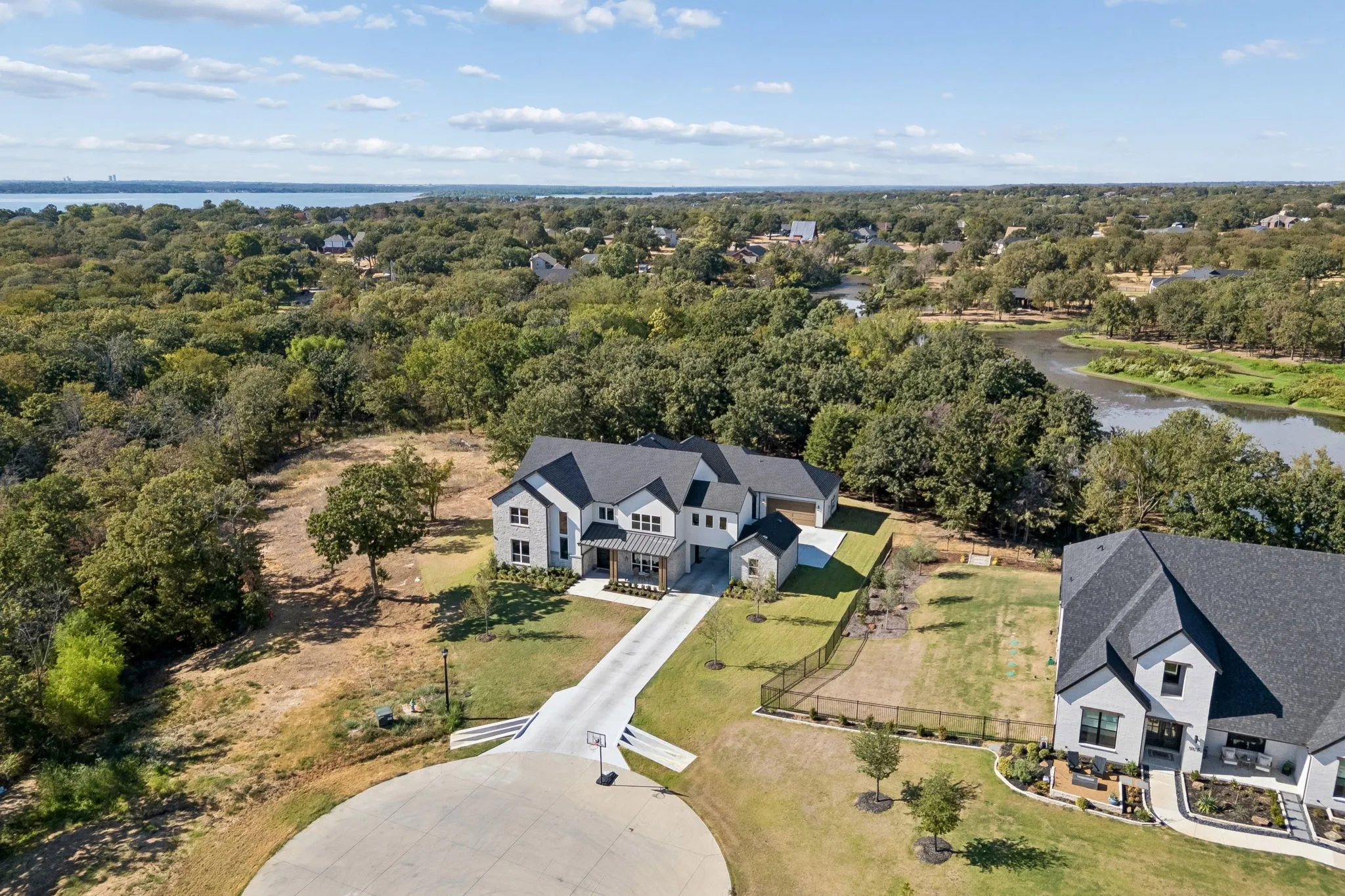 Contemporary residence with a dark shingle roof, light-colored siding, and a long driveway