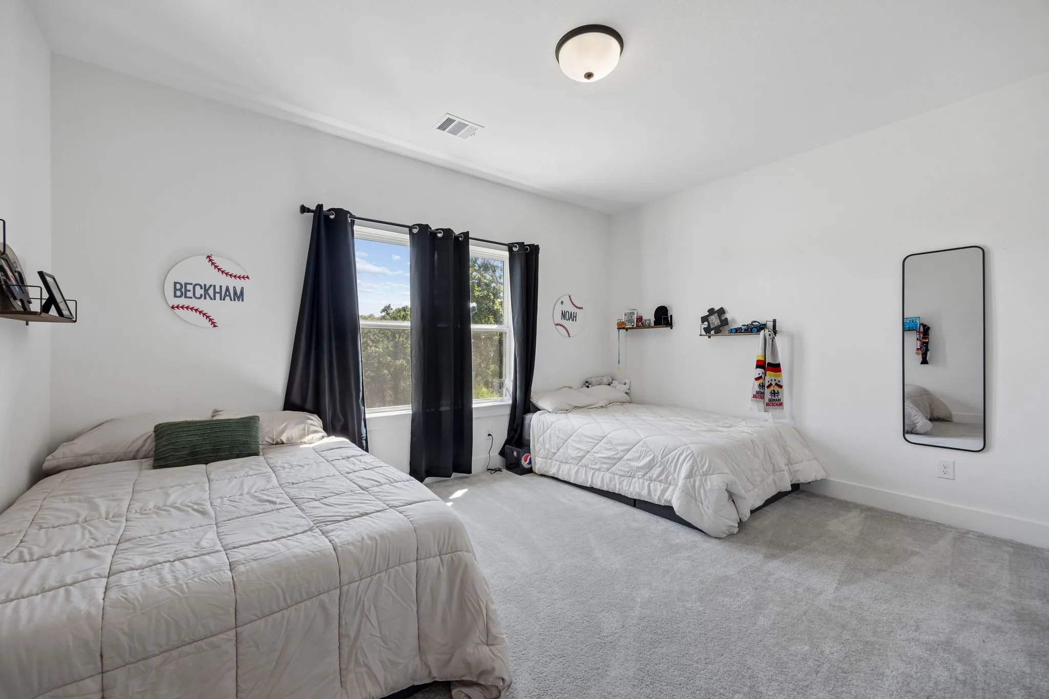 Light gray carpeting, white painted walls, and a prominent window with dark drapery
