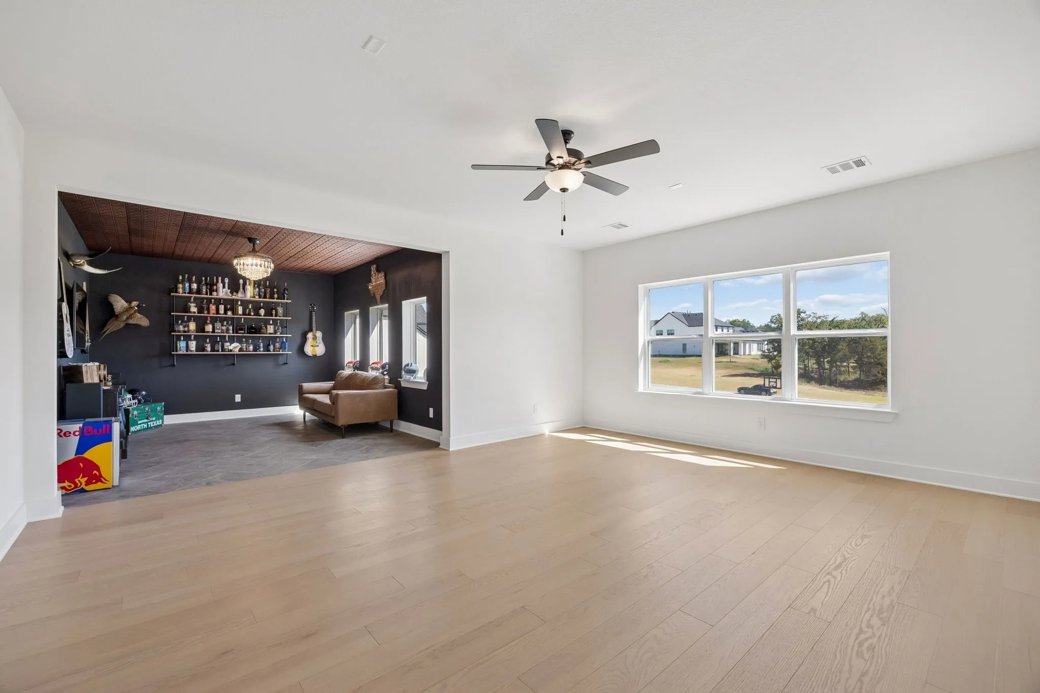Expansive room featuring wood-finish flooring, a contemporary ceiling fan, and a large multi-pane window