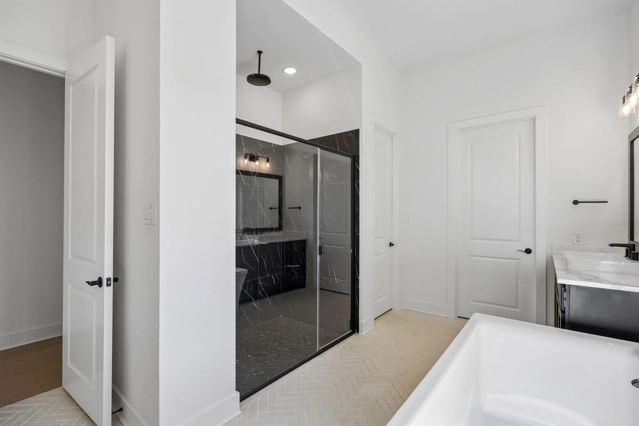Glass-enclosed shower with black-framed door and dark marble-look tile
