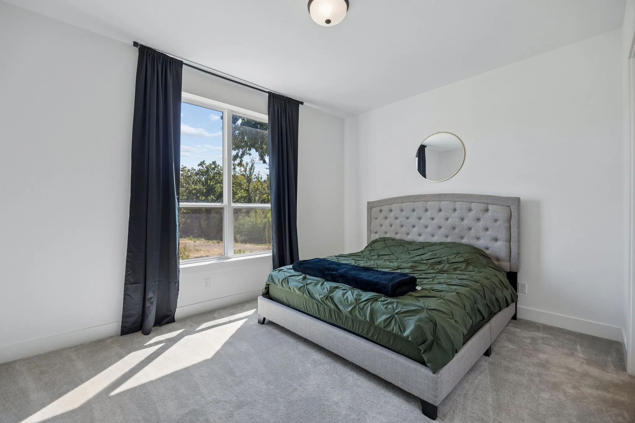 Carpeted bedroom featuring a large window, a flush-mount ceiling light, and white painted walls