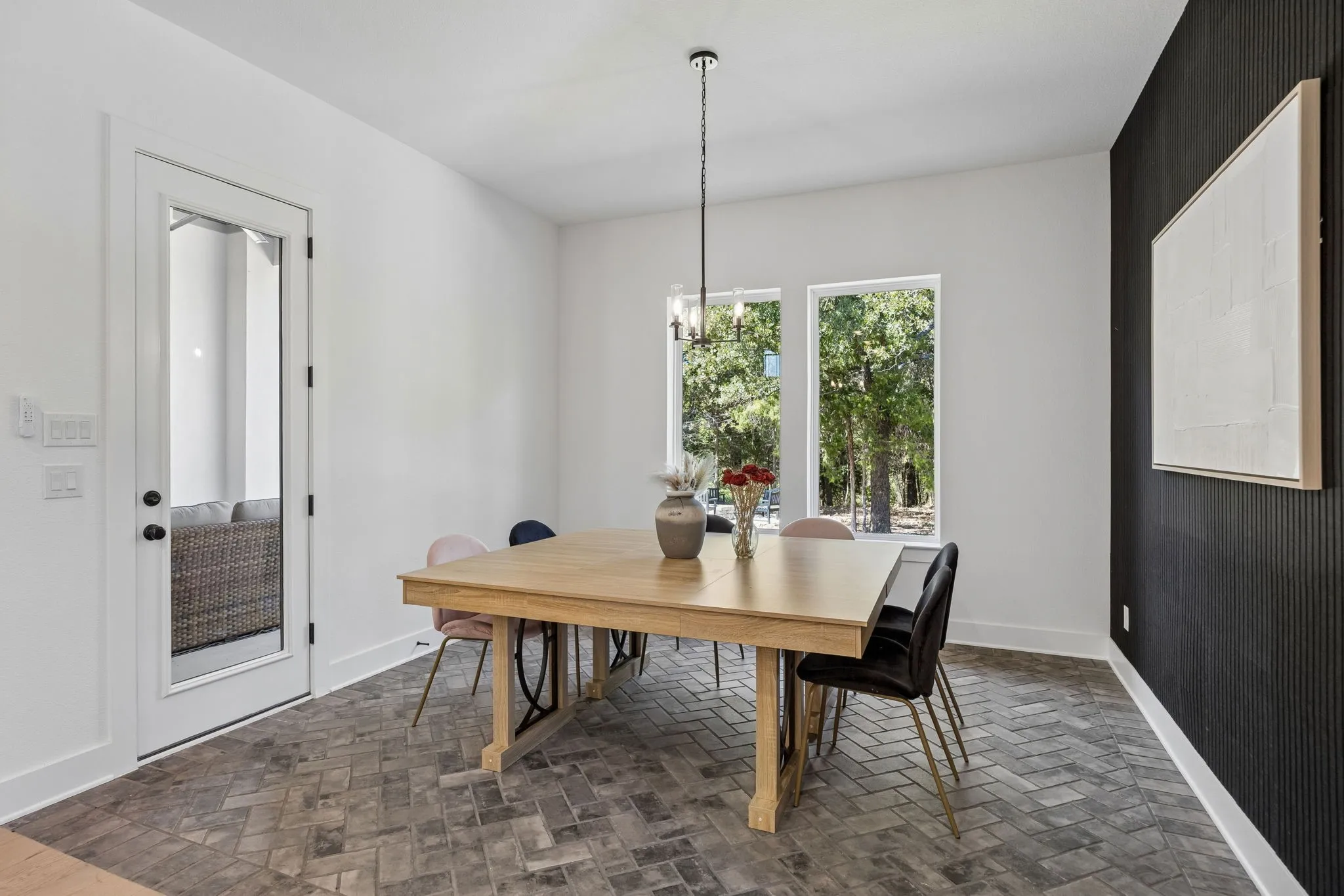 Dining area featuring herringbone-patterned flooring, a full-light exterior door, and two large windows