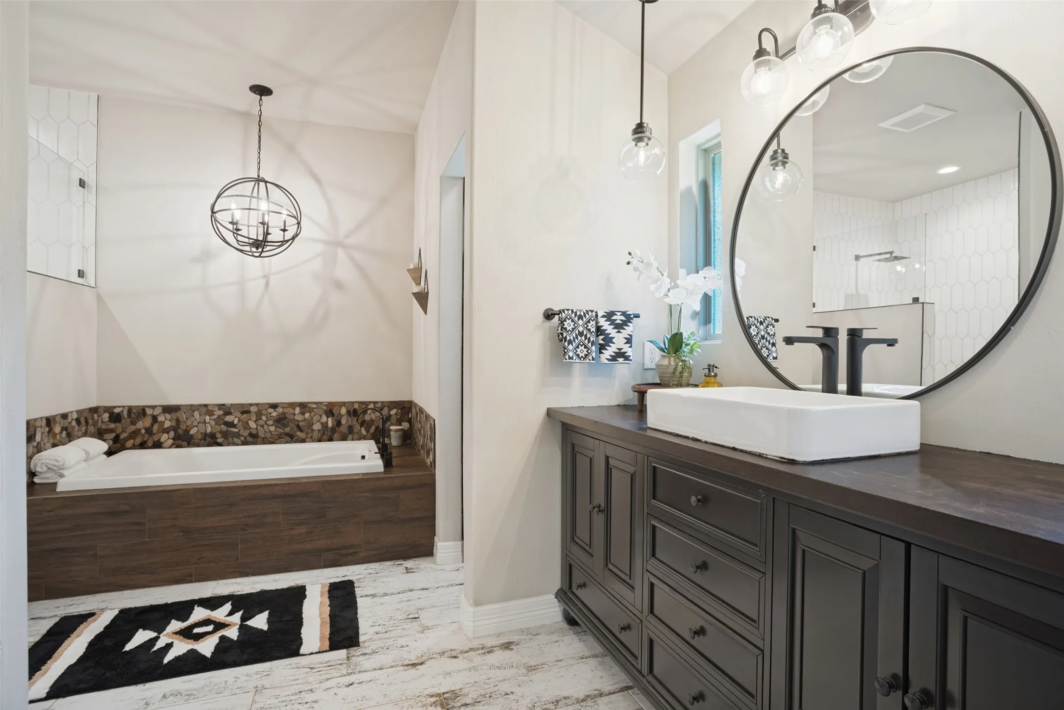 Beautifully remodeled primary bath with decorative lighting, separate tub and shower and walk in closet.